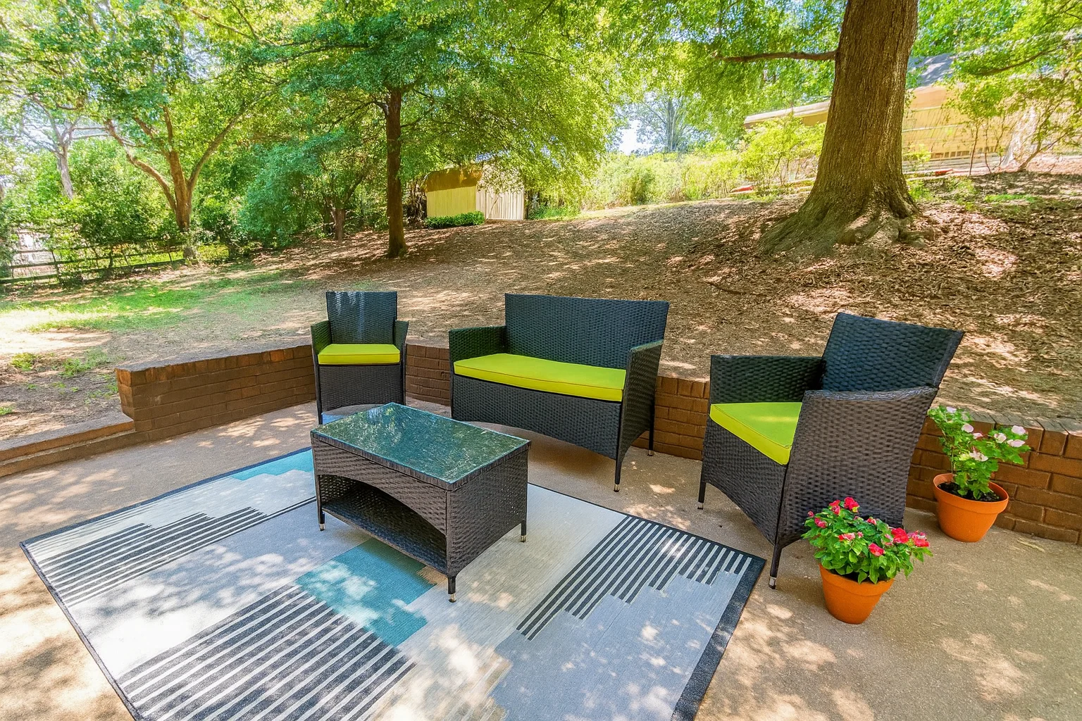 Modern patio with rattan furniture and green cushions under shade trees in Charlotte villa NASCAR All-Star Race
