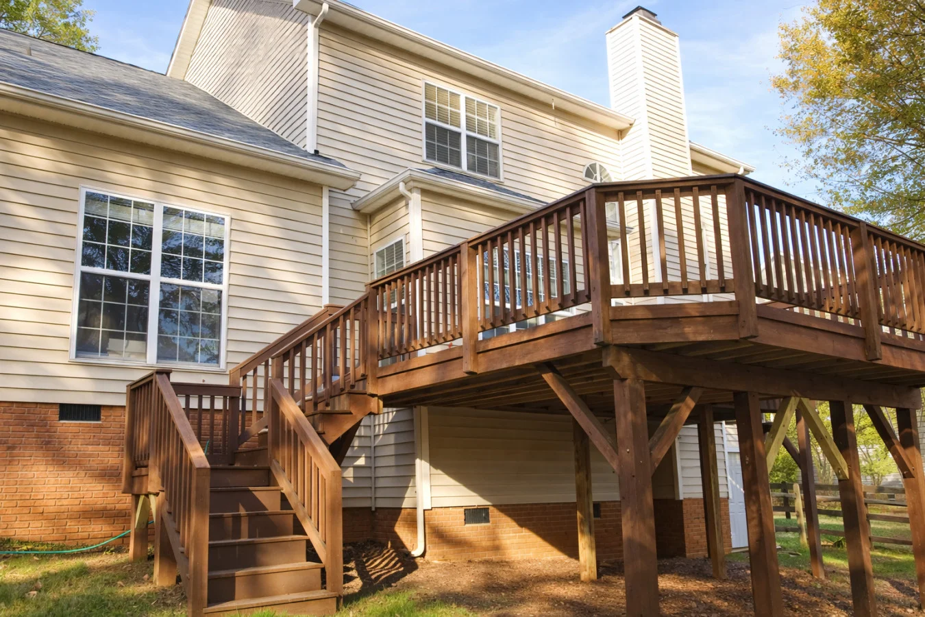 Suburban family-friendly vacation rental exterior near Charlotte NC with two-story home, wooden deck, and mature trees
