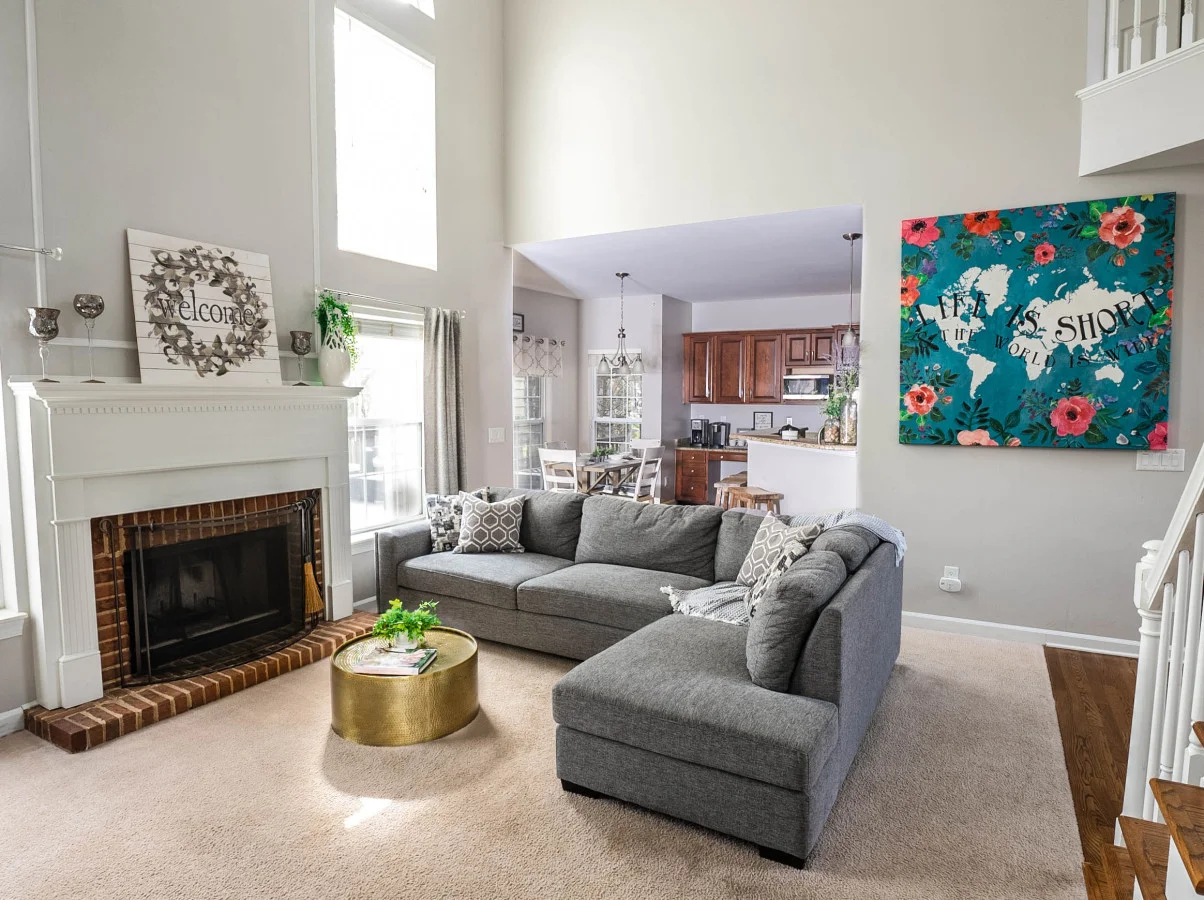 Bright living room with gray sectional sofa and fireplace in Charlotte area family retreat. 13 Best Day Trips From Charlotte, Picked by Locals
