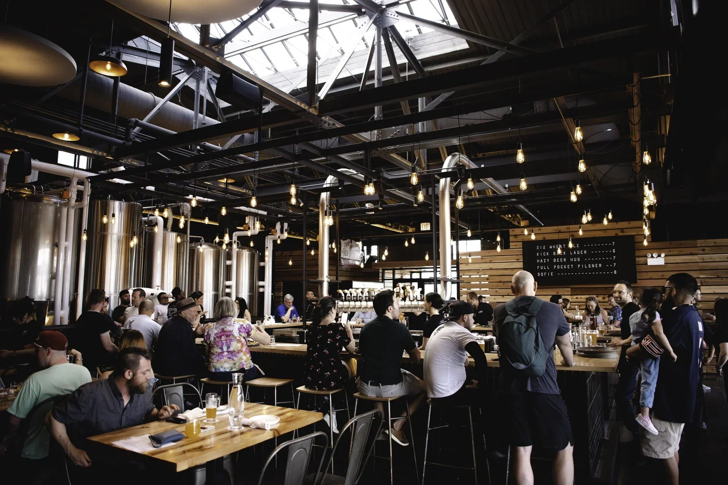 Chicago brewery taproom with steel fermentation tanks, wooden tables, and craft beer production facility walkthrough design