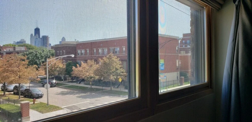 Urban street view through windows showing brick buildings, trees, and city skyline at Magic Factory Lofts West Loop Chicago