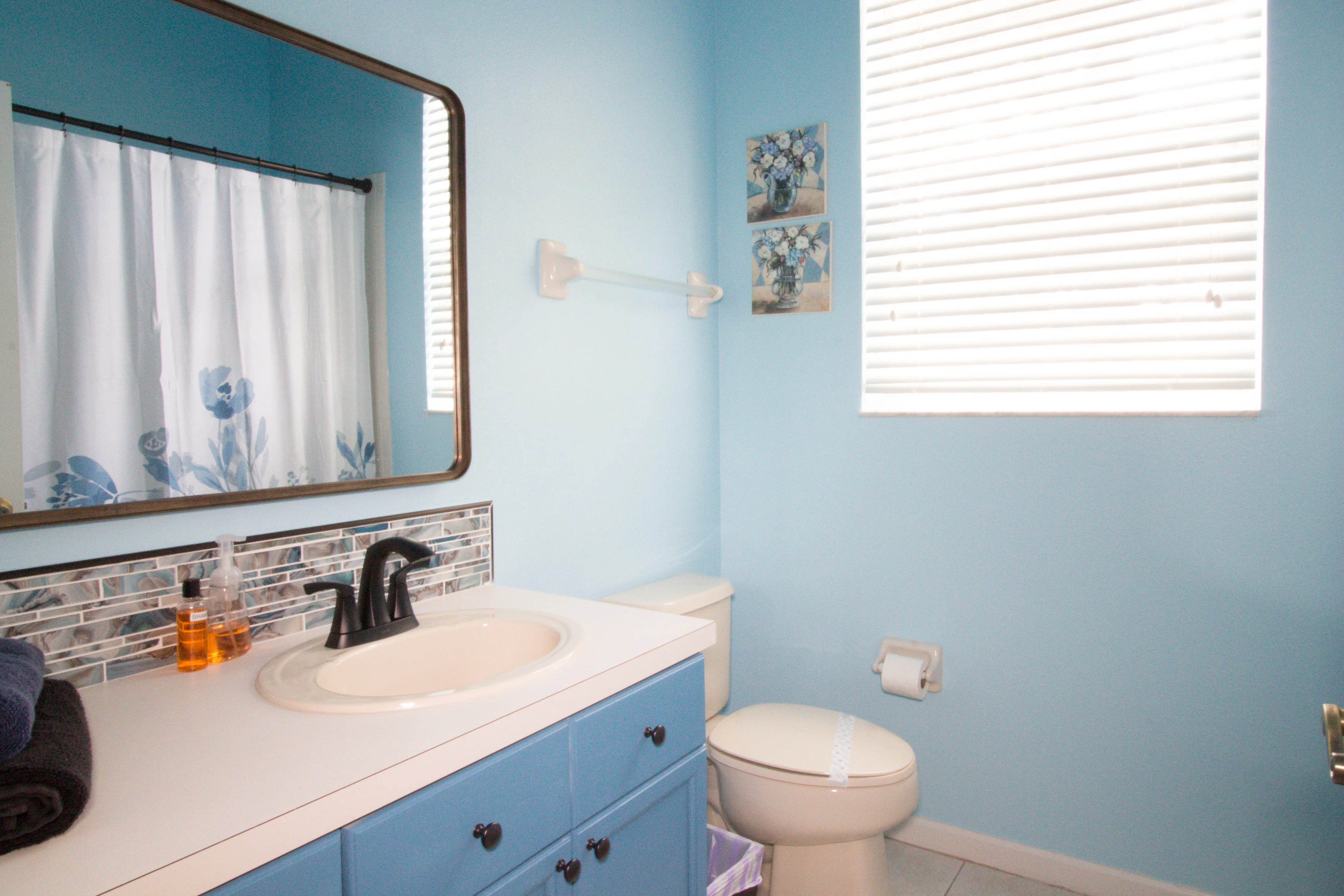 Bright modern bathroom with blue vanity and white countertop in Kissimmee vacation rental