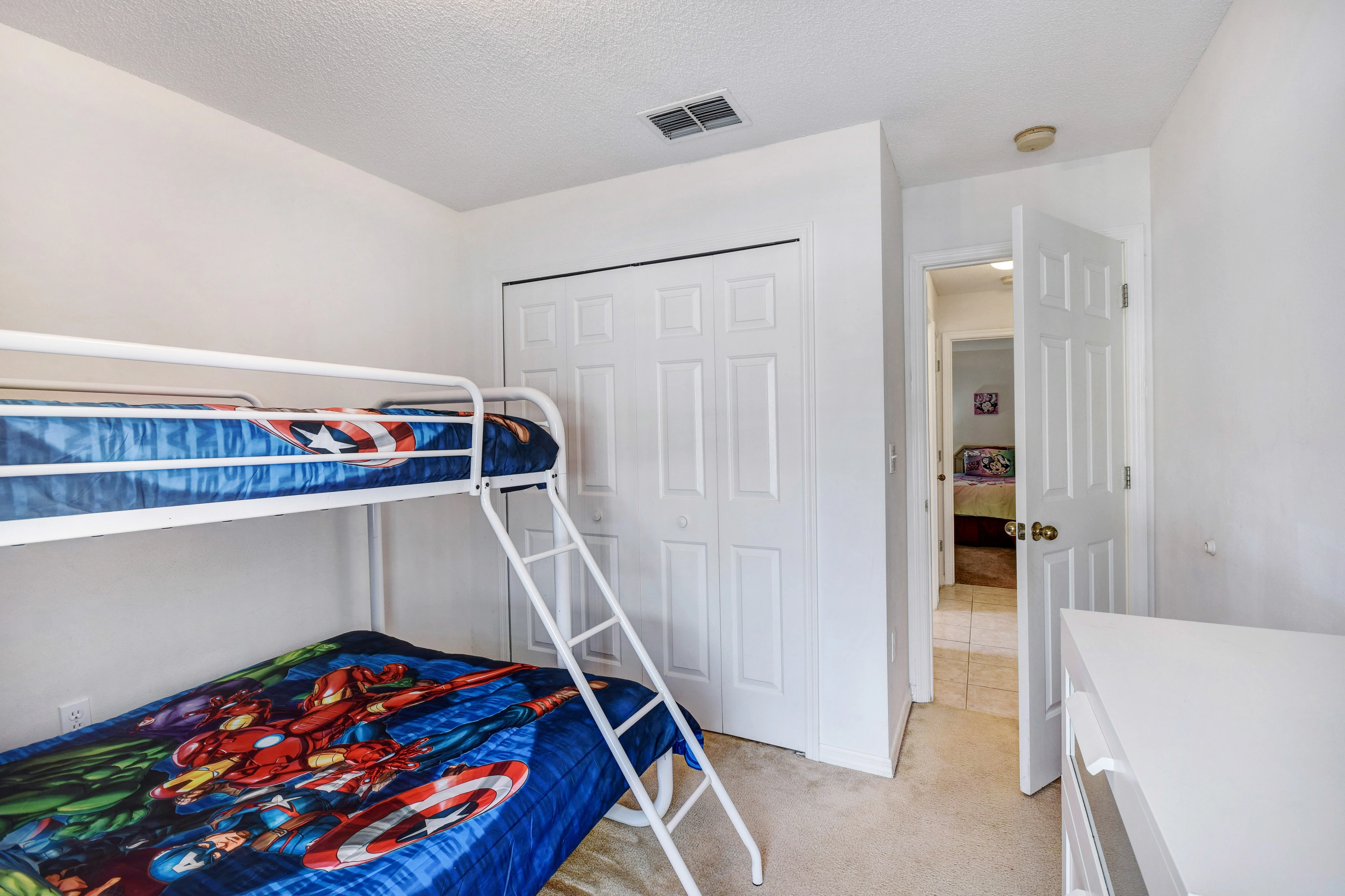Bright kids bedroom with white bunk beds and superhero bedding in luxury Kissimmee villa