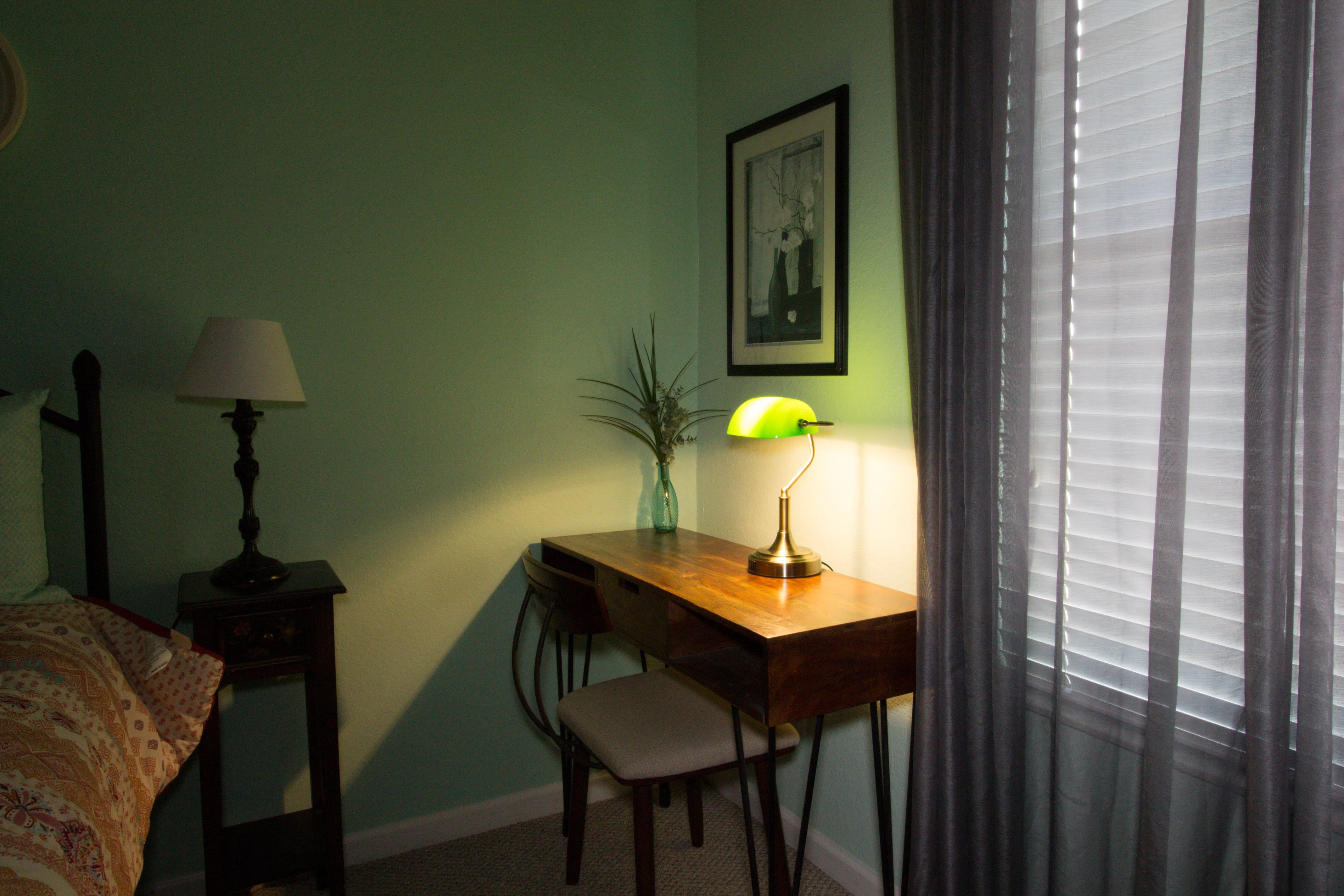 Sage green bedroom with wooden desk, vintage lamp, and natural light near windows in Orlando vacation villa rental