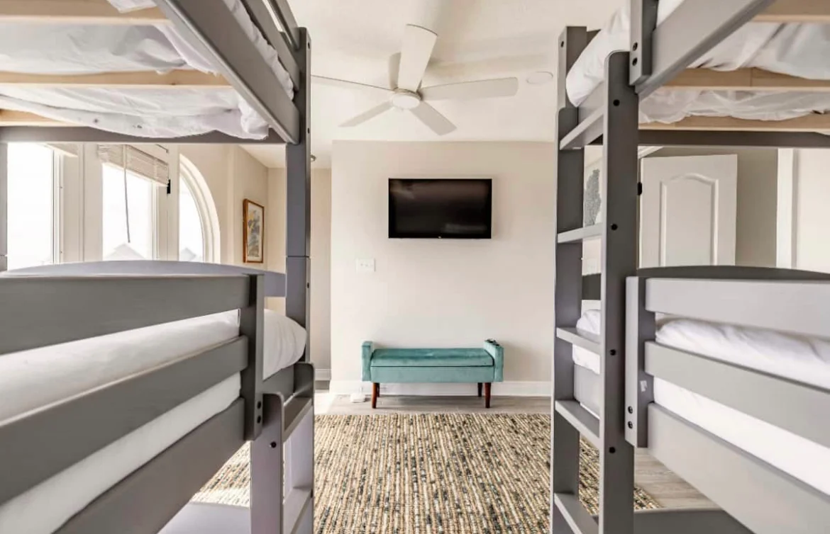 Modern dorm-style bedroom with multiple bunk beds and natural light in Panama City Beach house rental