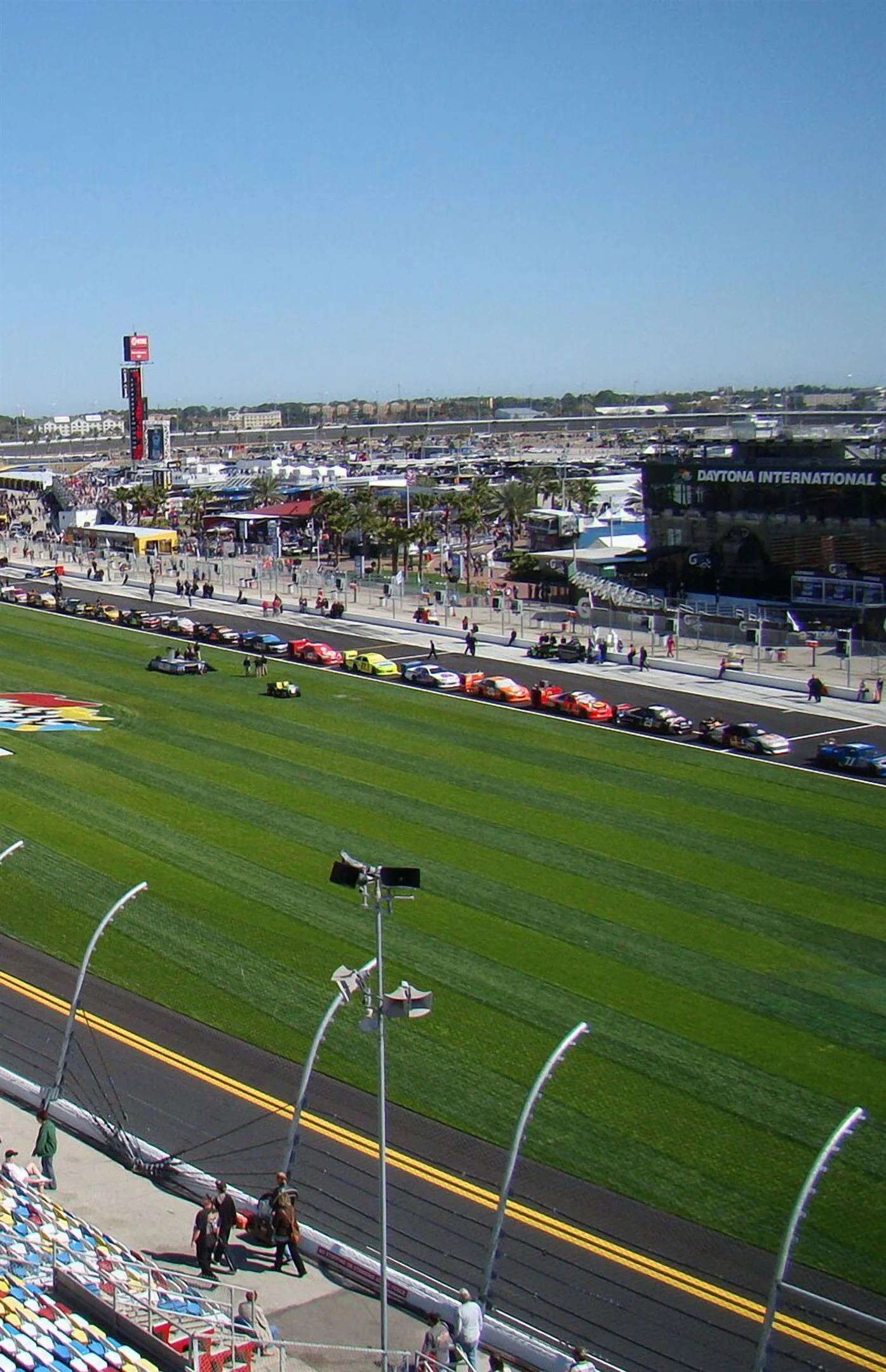 Daytona International Speedway race track with cars and grandstands under blue sky