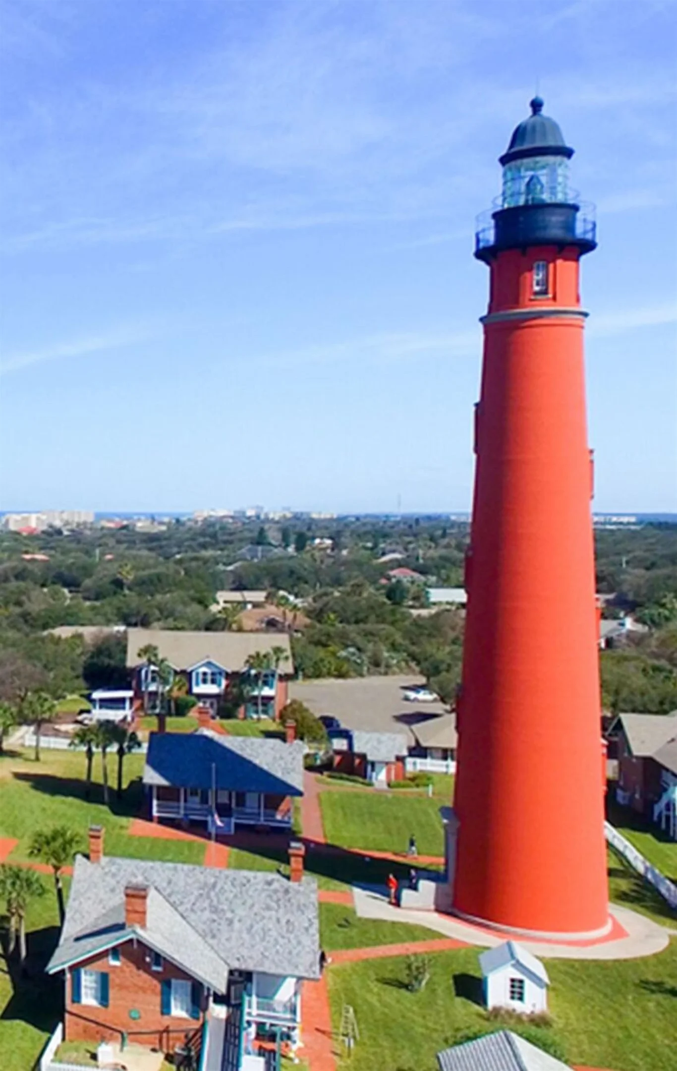 Red and black lighthouse with coastal homes and waterfront views in Daytona Beach