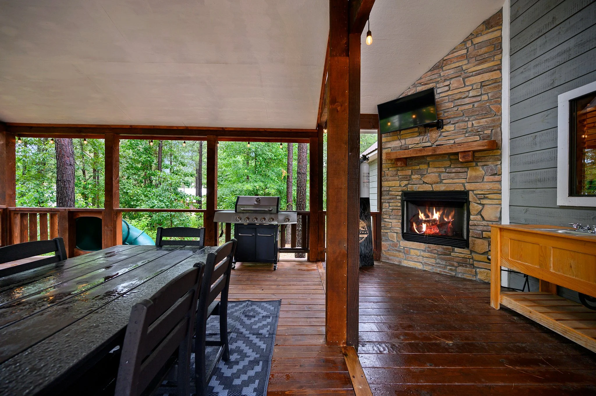Patio with stone fireplace and forest views at Endless Skyway Cabin in Broken Bow, Oklahoma