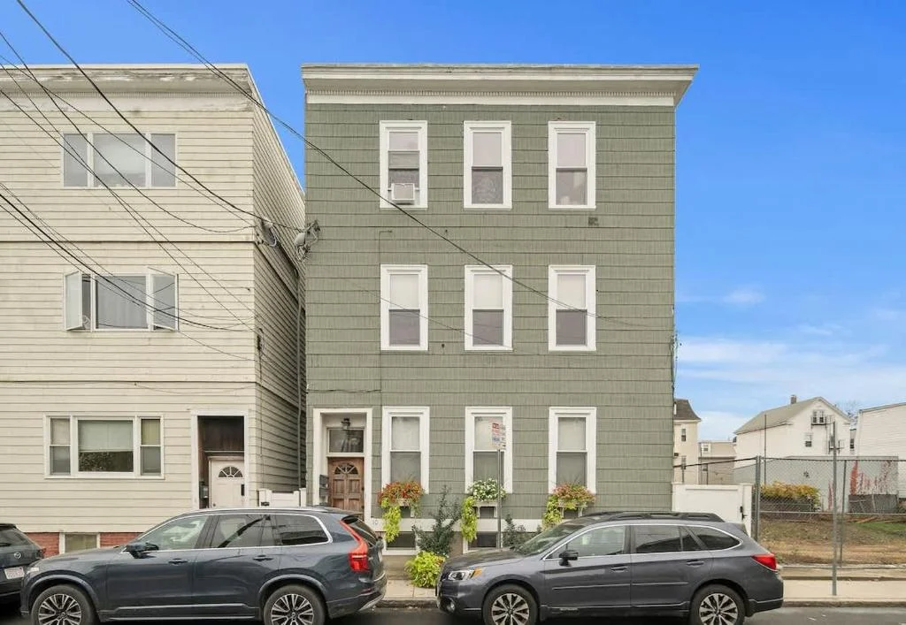 Three-story sage green townhouse with white-trimmed windows and welcoming entrance, illustrating management fees in a