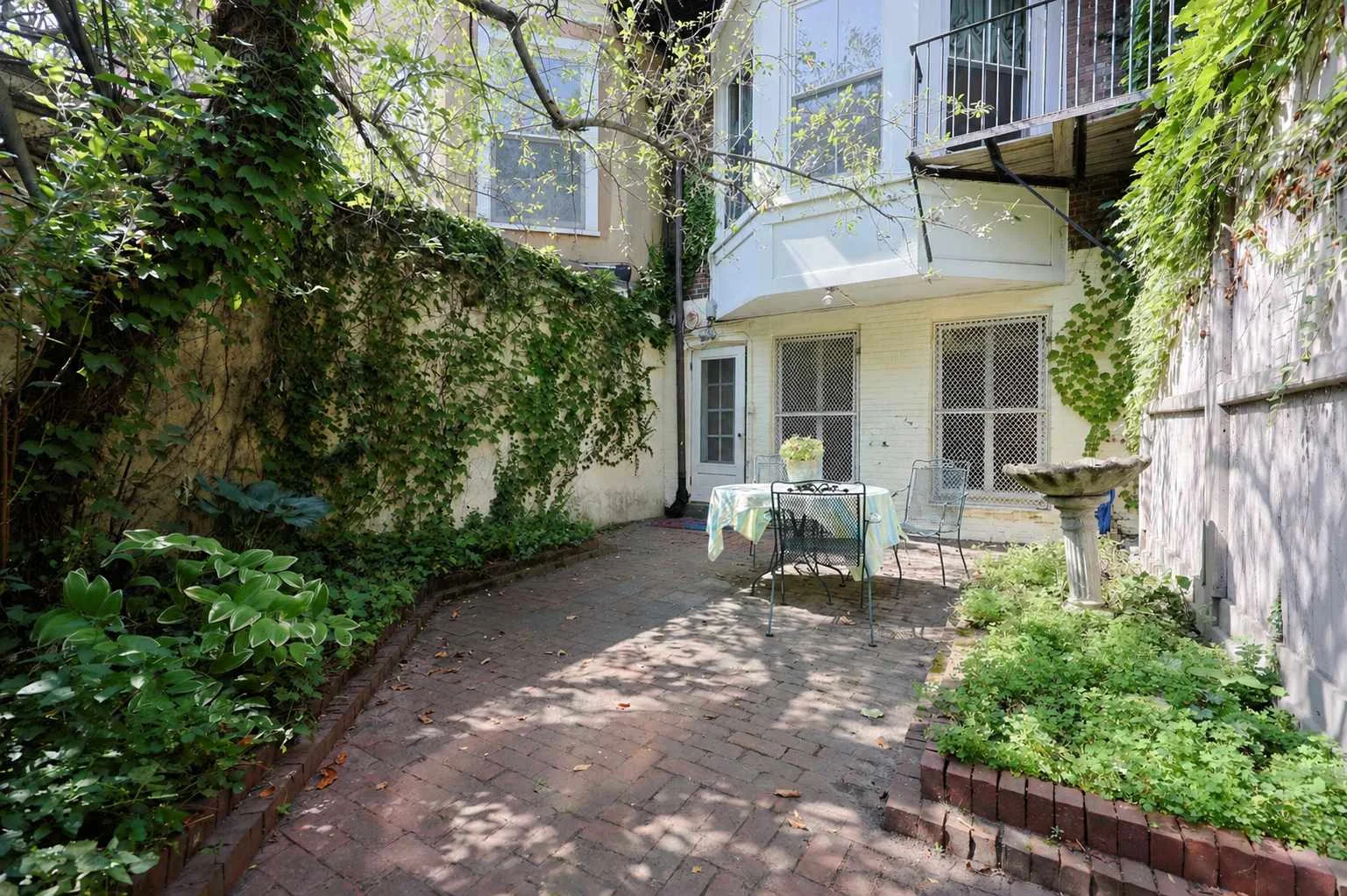 Private brick patio with ivy-covered walls and outdoor dining in Boston brownstone rental