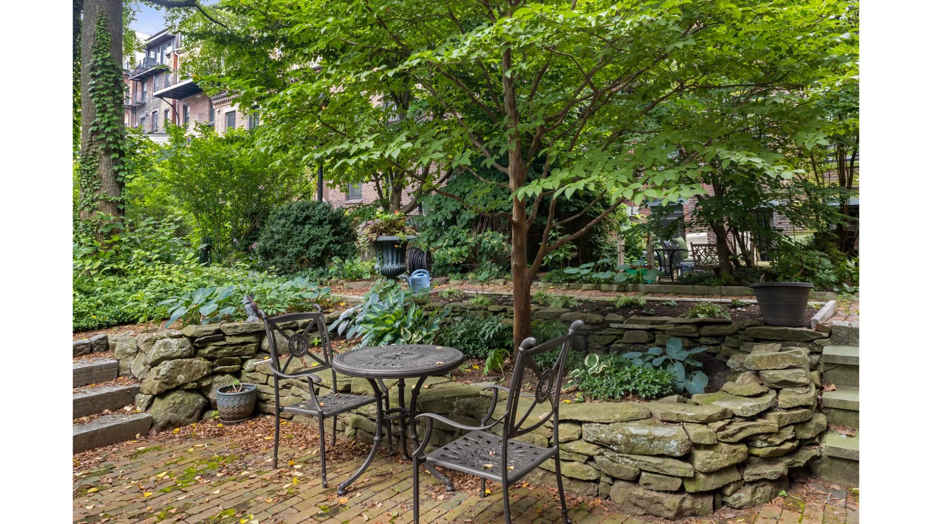 Private patio with round table, ornate chairs, and urban garden in Boston
