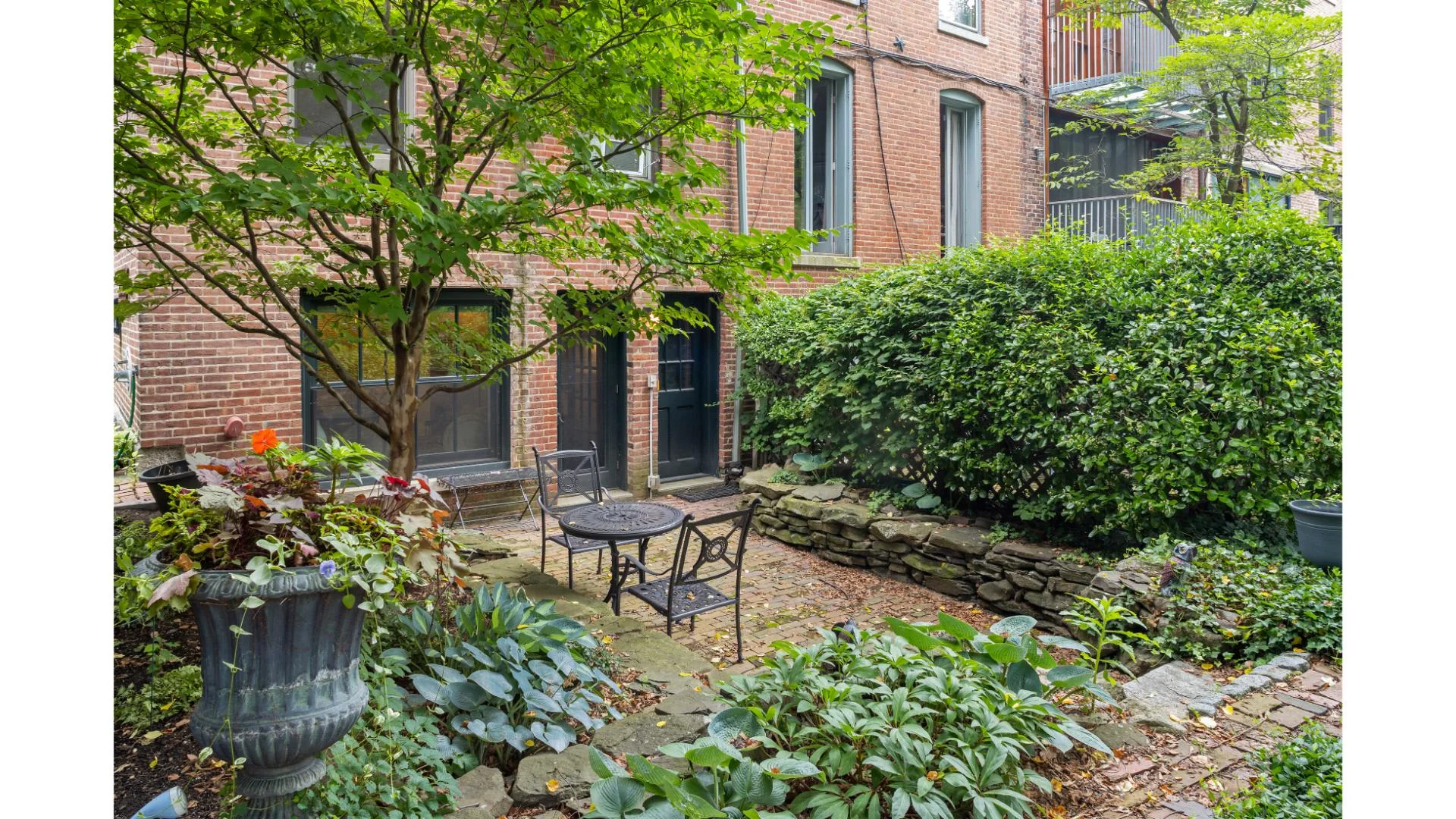 Private brick patio with planters, ivy and wrought iron seating at a Boston townhouse in the South End Hospitality portfolio