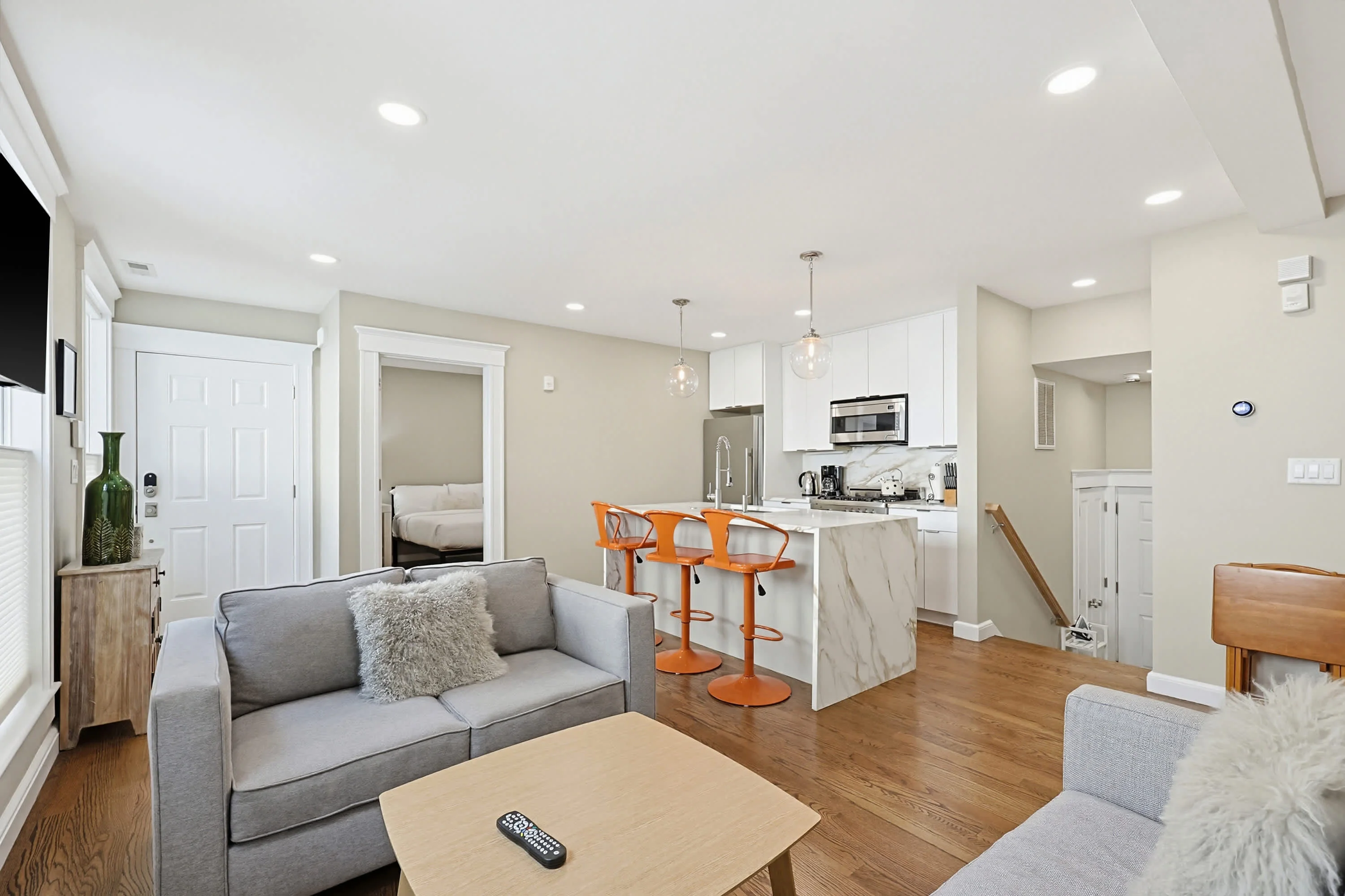 Modern Cambridge living room with kitchen access, neutral decor, and contemporary furniture in vacation rental