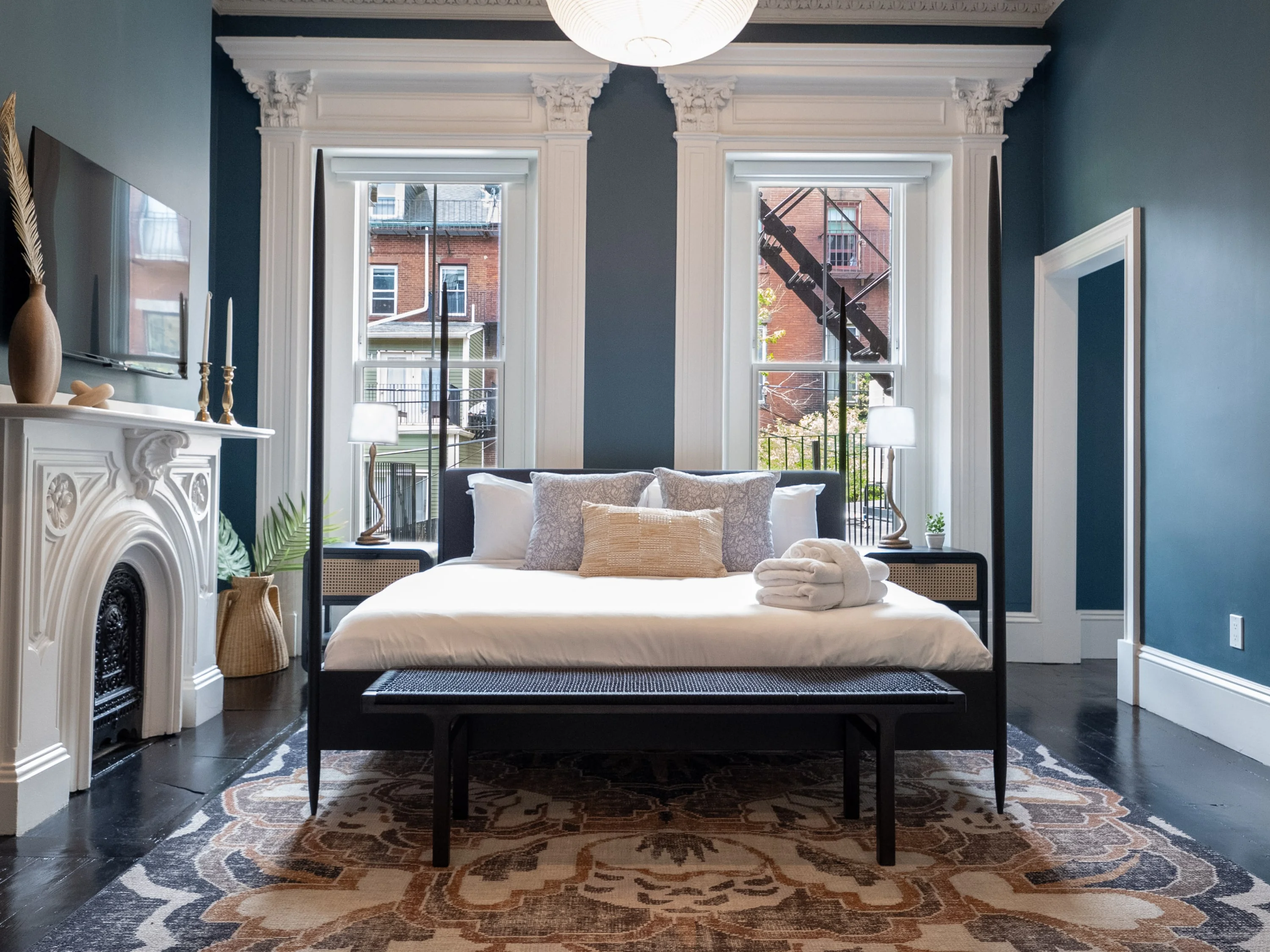 Penthouse bedroom with fireplace and tall windows, a South End base for things to do in Boston