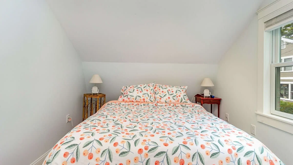 Bright attic bedroom with queen bed, floral bedding, and natural light in Gloucester MA vacation rental