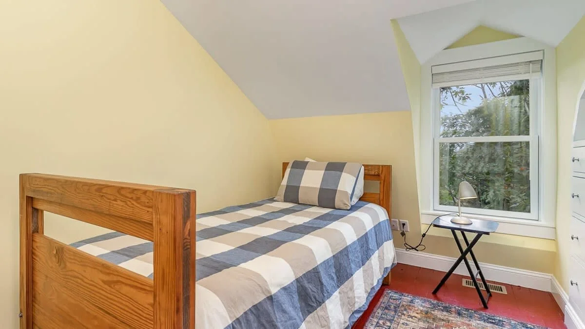 Bright guest bedroom with single bed, yellow walls, skylights, and work desk in Gloucester vacation rental