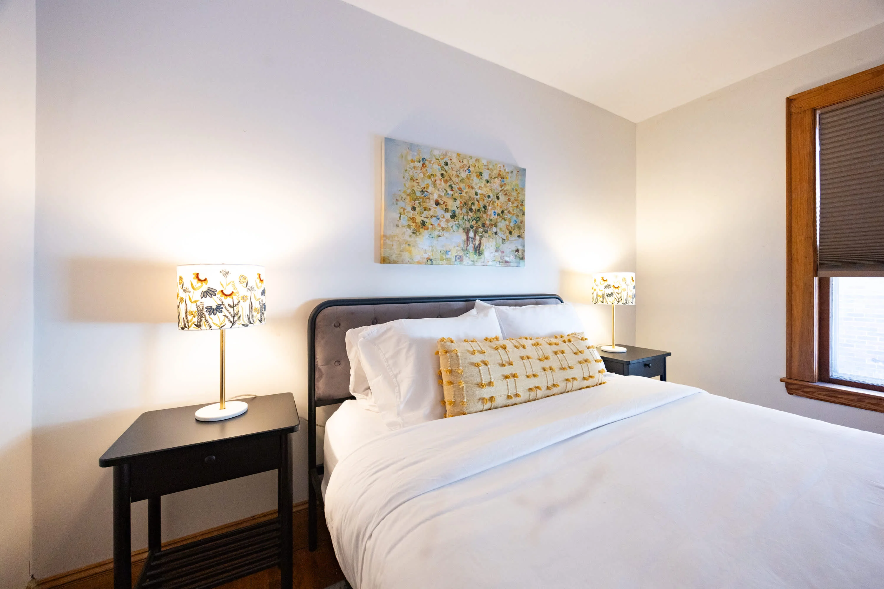Housekeeper making bed with white linens in bright bedroom for Boston rental turnover cleaning
