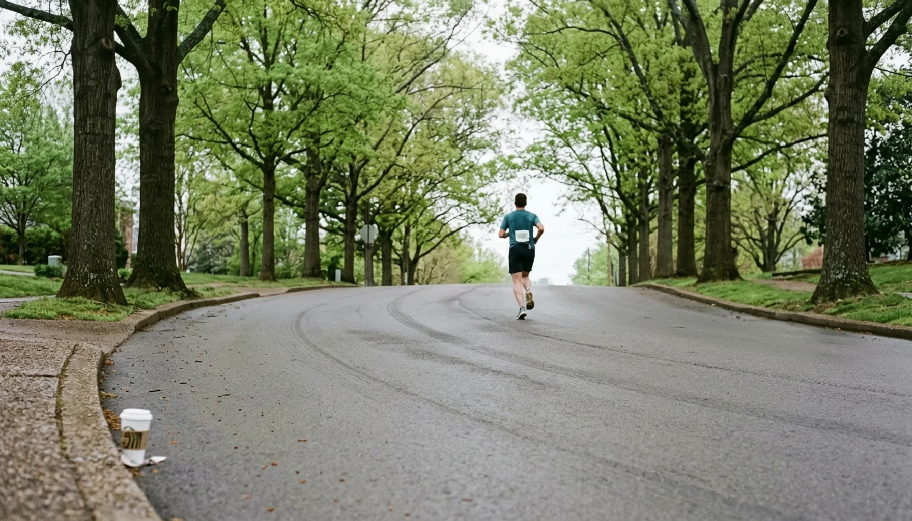 Lone runner seen from behind cresting a hill on a Nashville street course during the Nashville Rock n Roll Marathon training run at dawn.