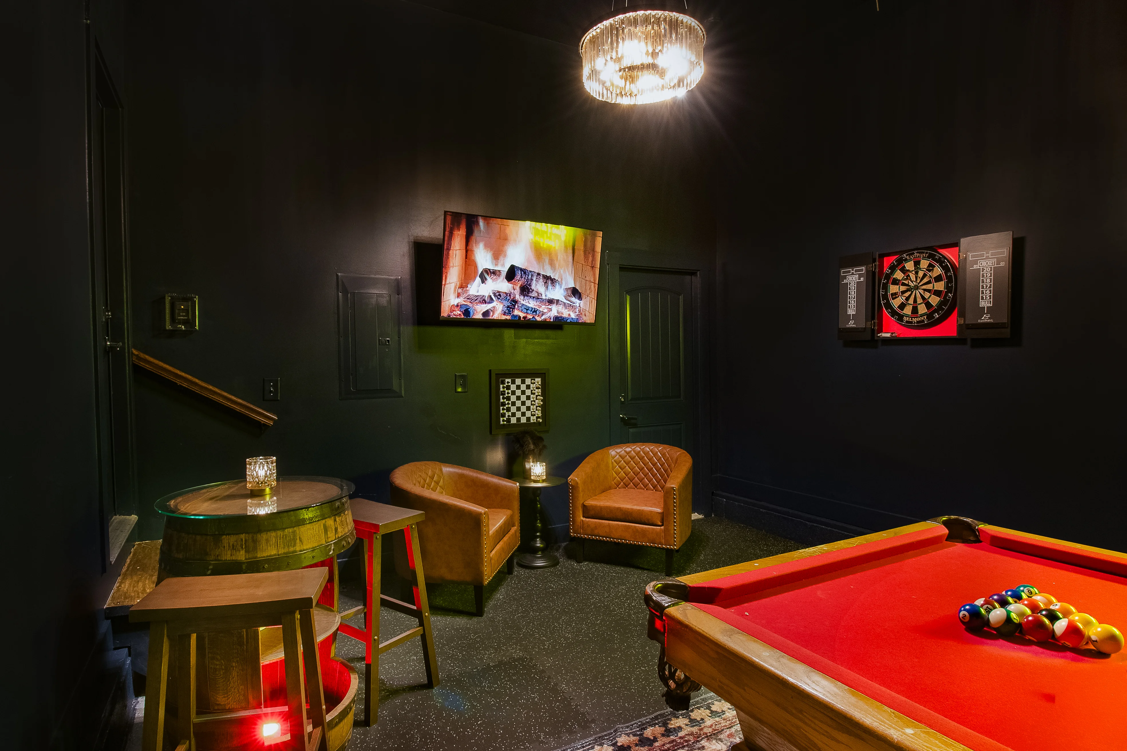 Speakeasy game room with billiards table, leather chairs, dartboard, and neon bar atmosphere at Underwood Manor