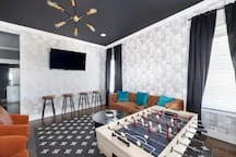 Modern game room with foosball table, wall-mounted TV, and bar seating at Fern A Nashville