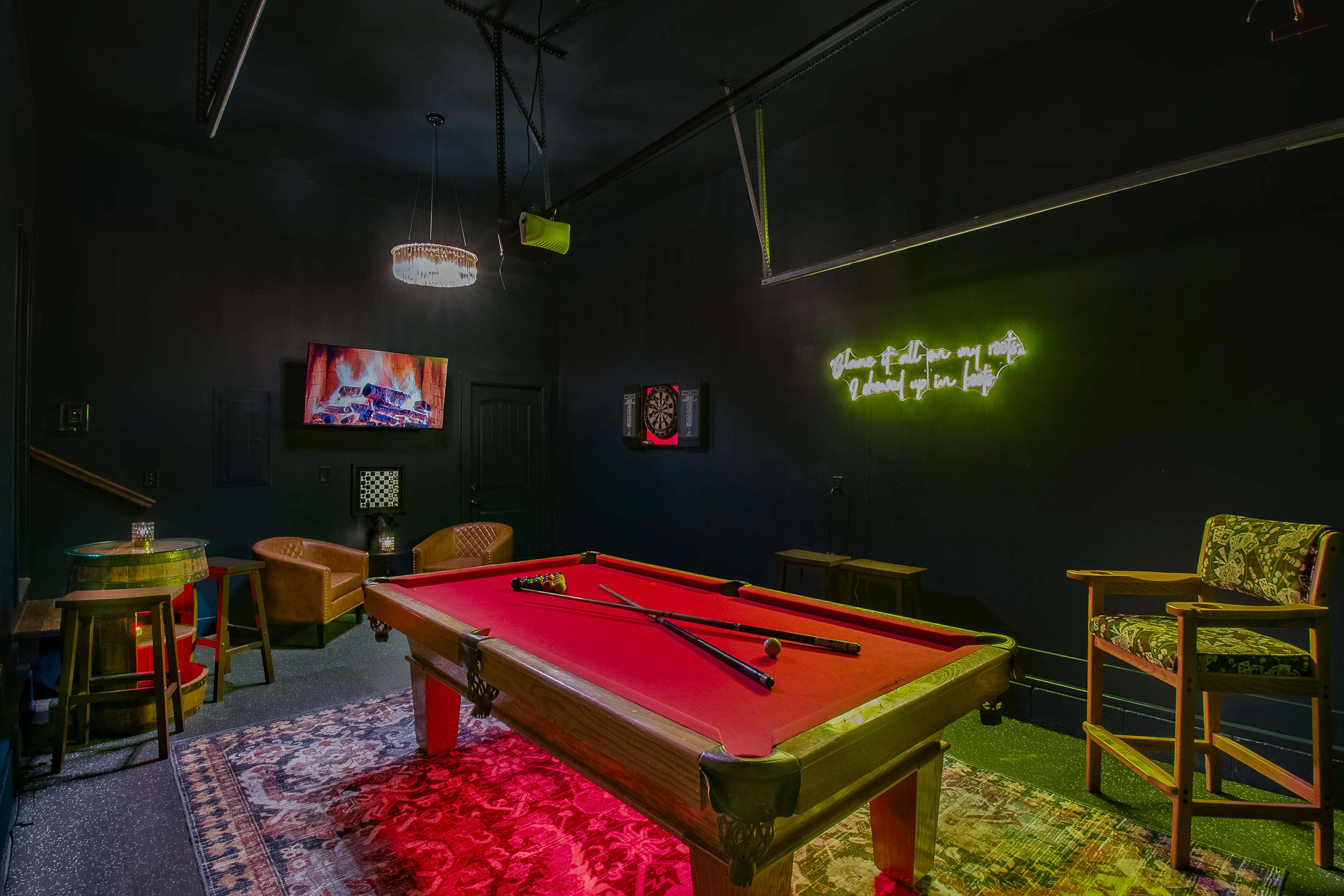 Modern game room with red and green pool table and neon signs at Underwood Manor in Nashville