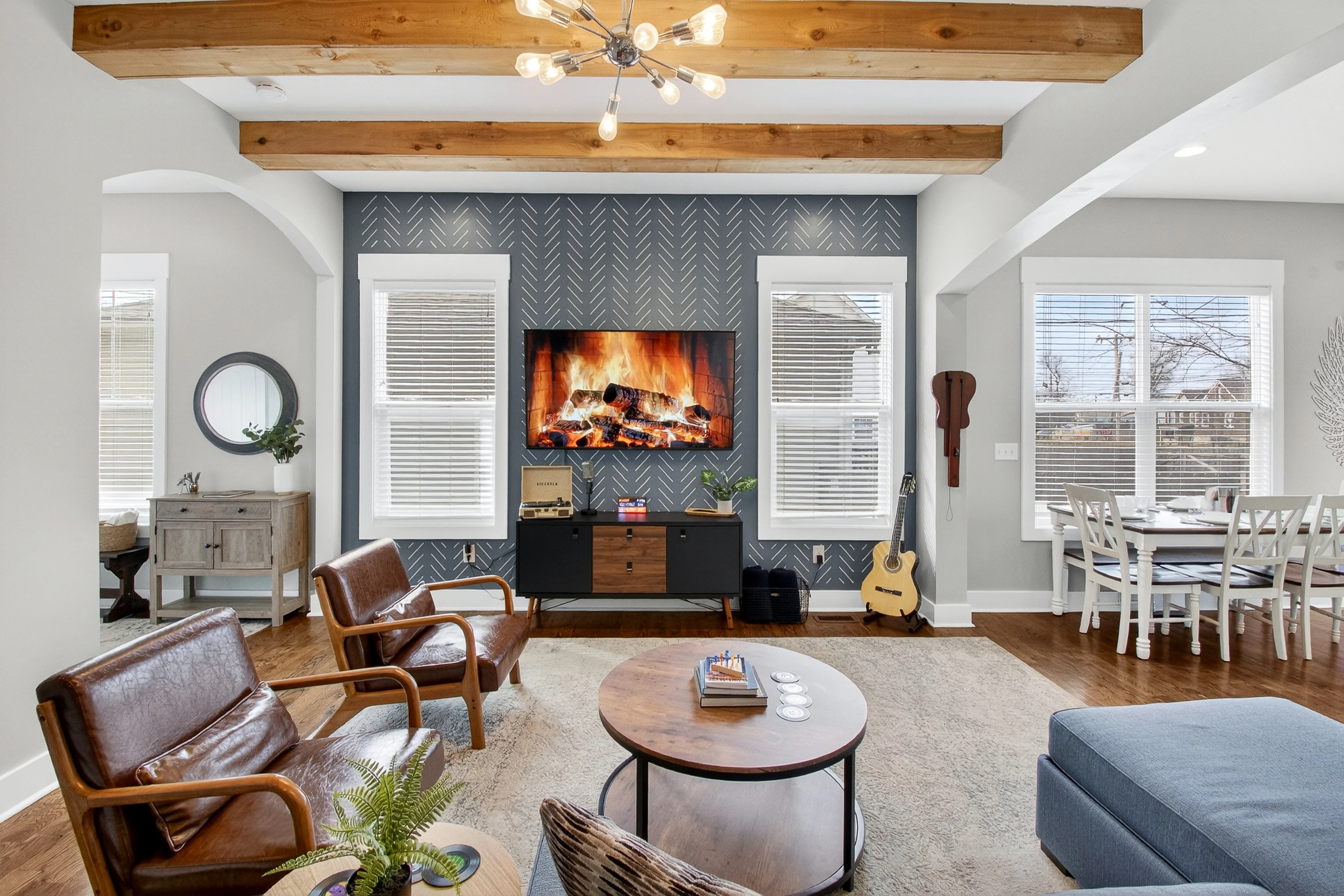 Modern living room with exposed wooden beams, herringbone fireplace, and mid-century furniture creating an authentic