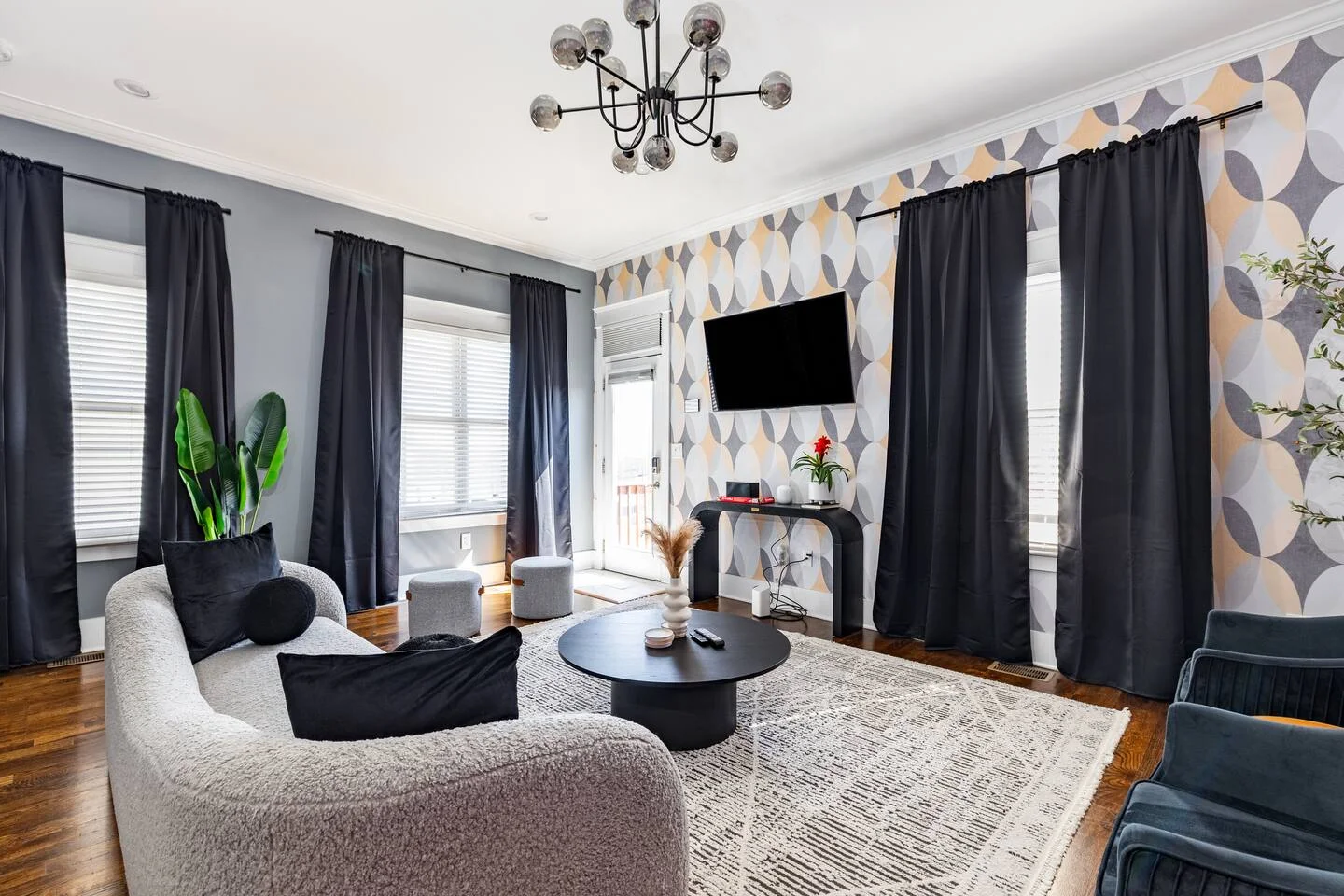 Modern living room with curved cream sofa, geometric wallpaper, and black accents in Nashville speakeasy game room