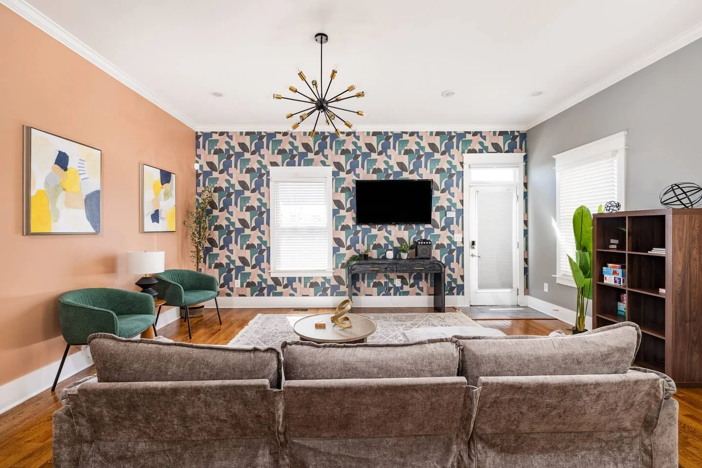 Modern living room with gray sectional, peach accent wall, and geometric feature wall design