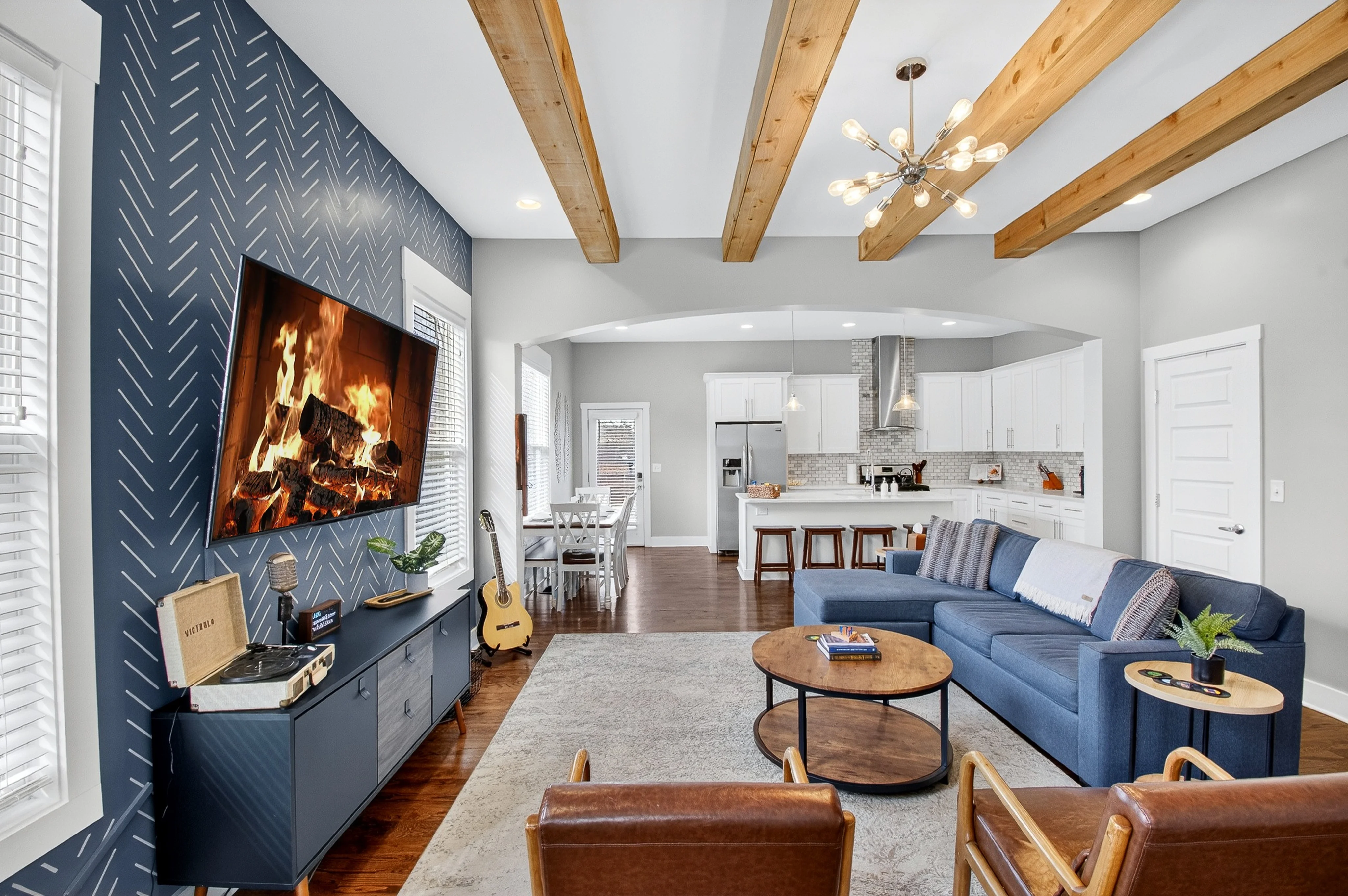 Modern Airbnb Nashville living room with blue accent wall, fireplace, and exposed wood beams at Underwood Manor