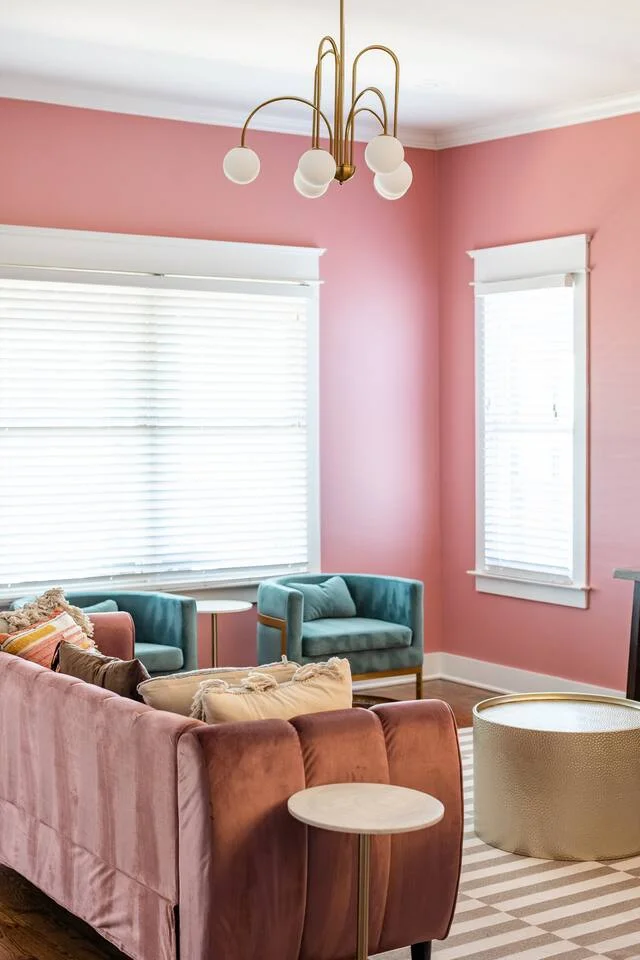 Modern living room with pink velvet sofa and brass chandelier, ideal for Nashville bachelorette party planning