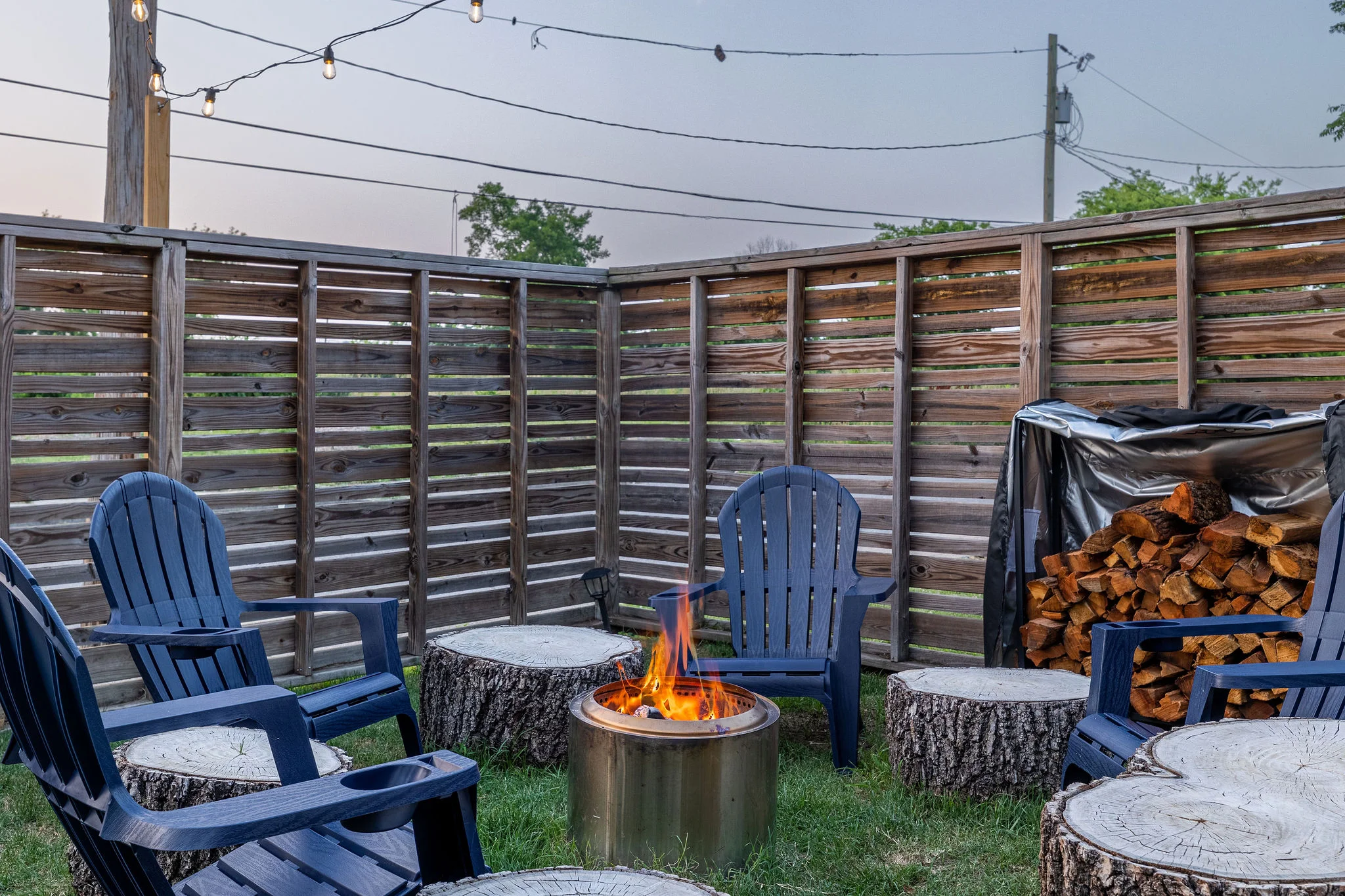 Rustic backyard patio with blue Adirondack chairs around fire pit at Underwood Manor