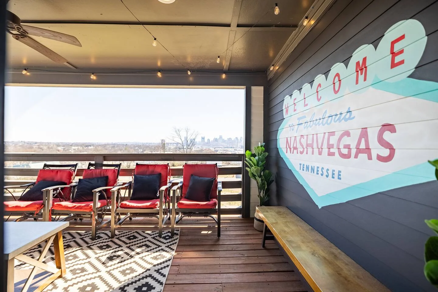 Rooftop patio with Nashville skyline views, modern lounge chairs, and neon sign for bachelorette party planning in Nashville