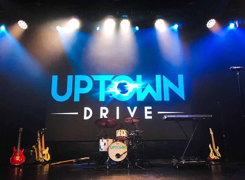 Concert stage with illuminated Uptown Drive sign and live music performance setup in Austin