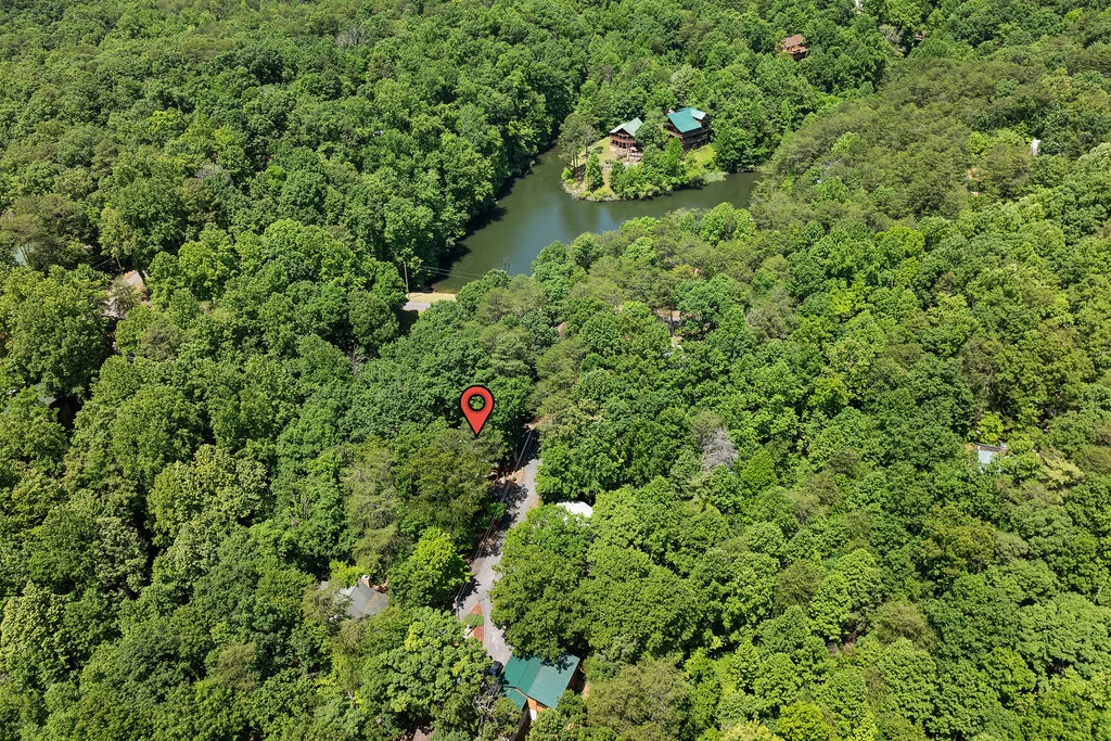 Aerial view of secluded cabin in dense forest with winding creek through hidden hiking trails near Sevierville Tennessee