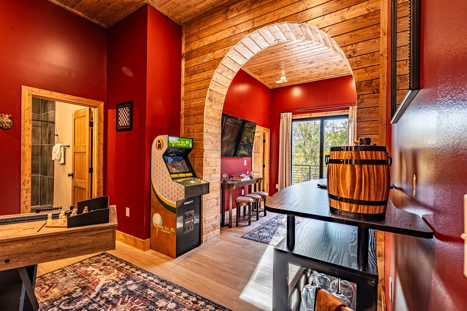 Game room with pool table and arcade in rustic log cabin with red walls and wooden beams, vacation rental in Pigeon Forge