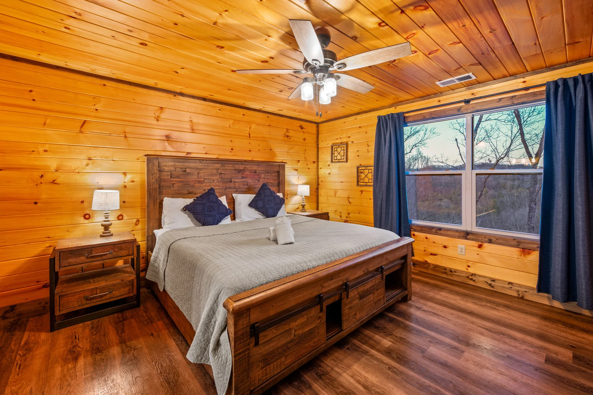 Rustic log cabin master bedroom with wooden bed, forest views, and warm wood paneling in Sevierville Tennessee cabin rental