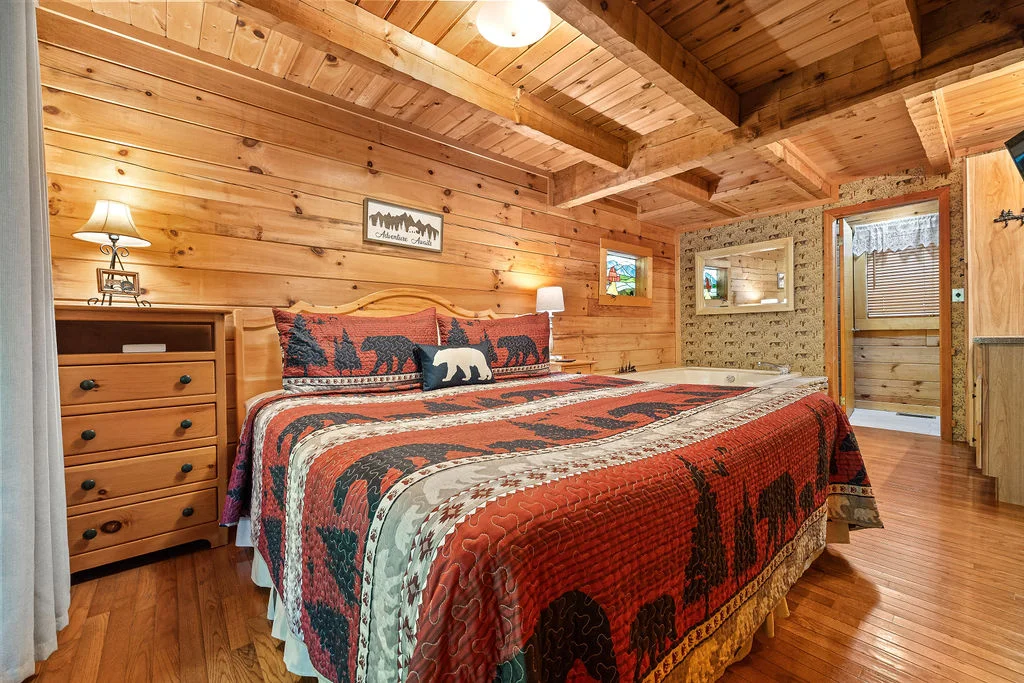 Rustic log cabin bedroom with exposed beams and bear-patterned bedding in Sevierville Tennessee