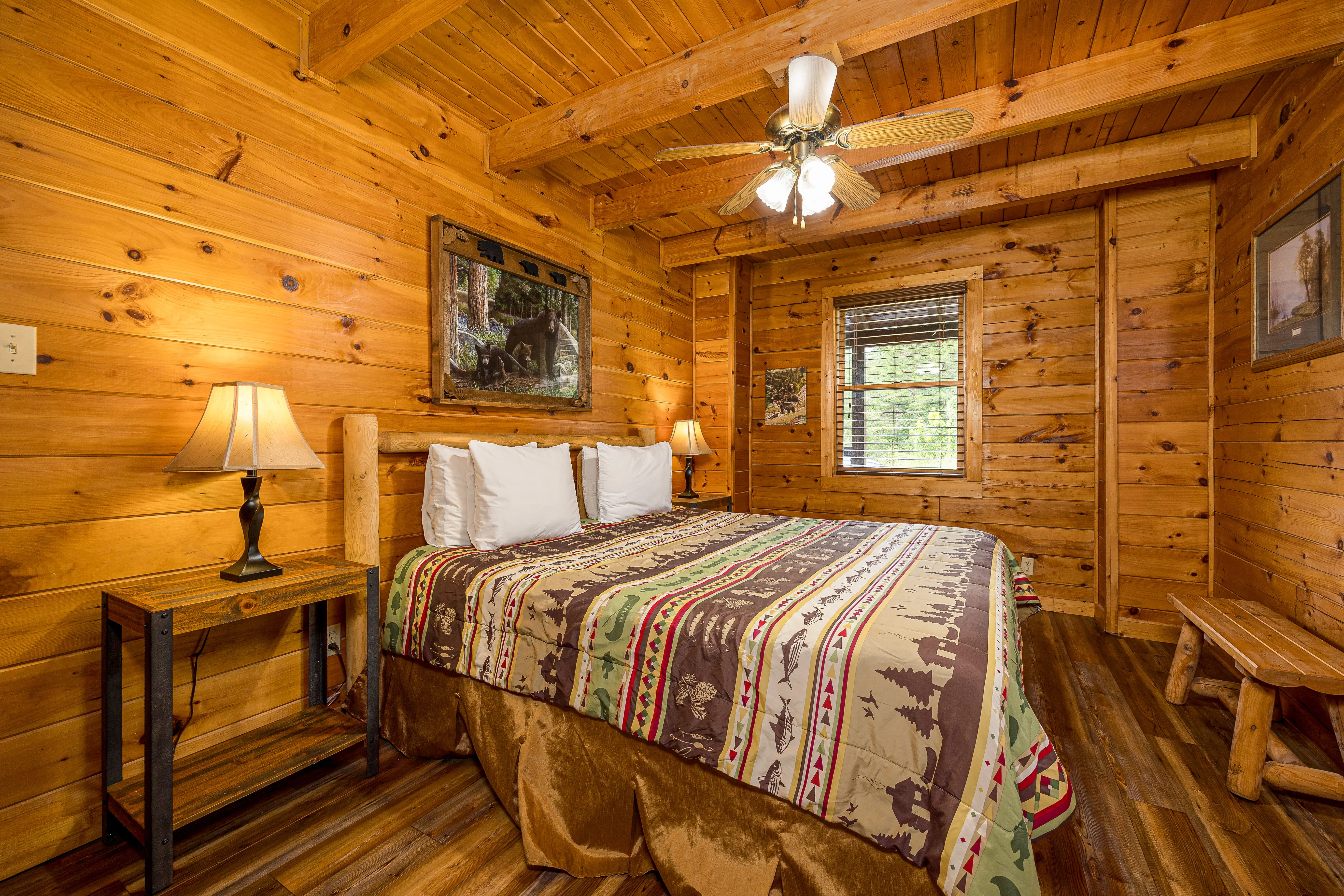Cozy log cabin bedroom with knotty pine walls, queen bed, and warm lighting in Sevierville mountain retreat