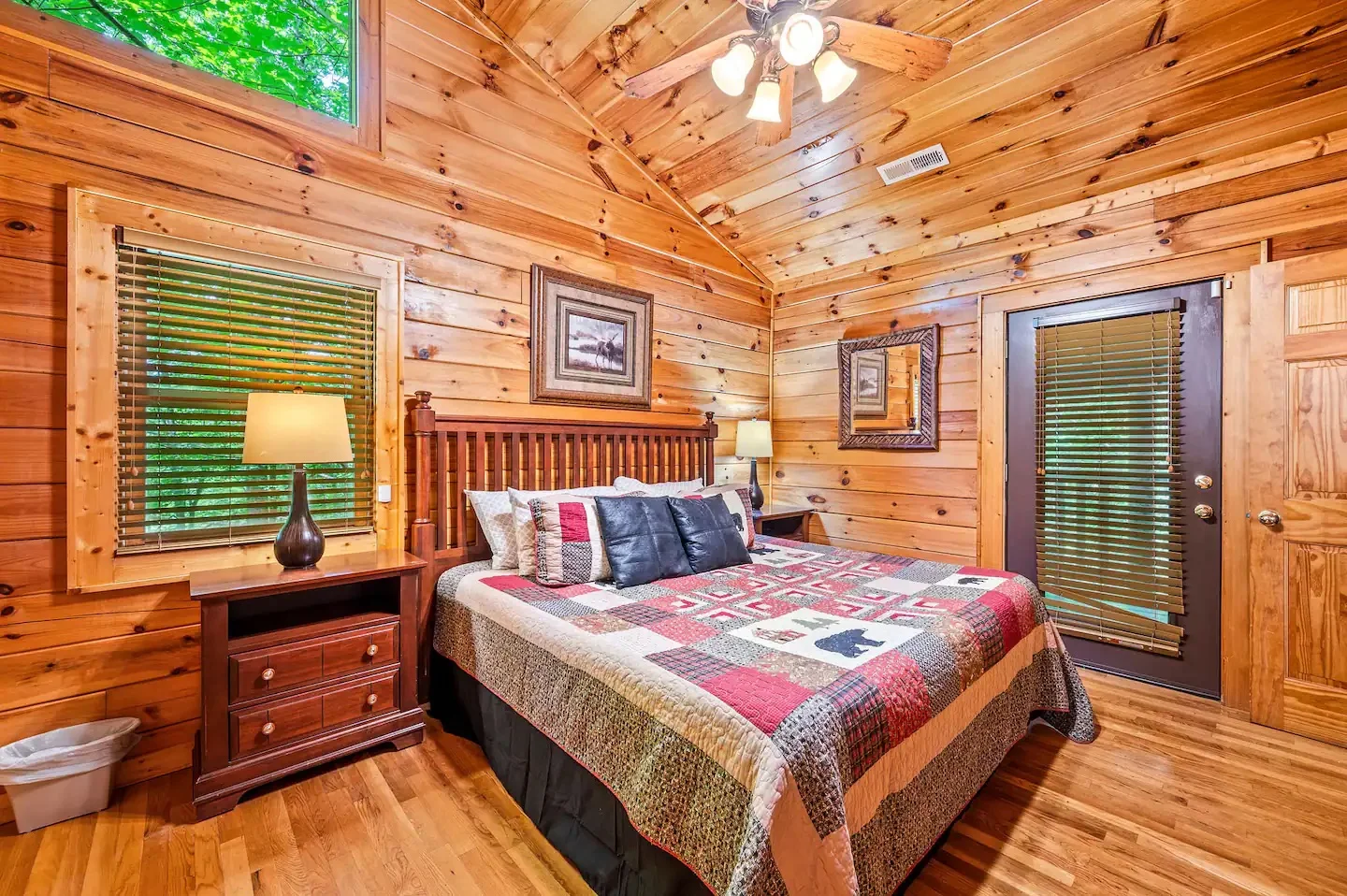 Rustic log cabin bedroom in Pigeon Forge area with knotty pine walls, queen bed, and forest views after a dinner show evening