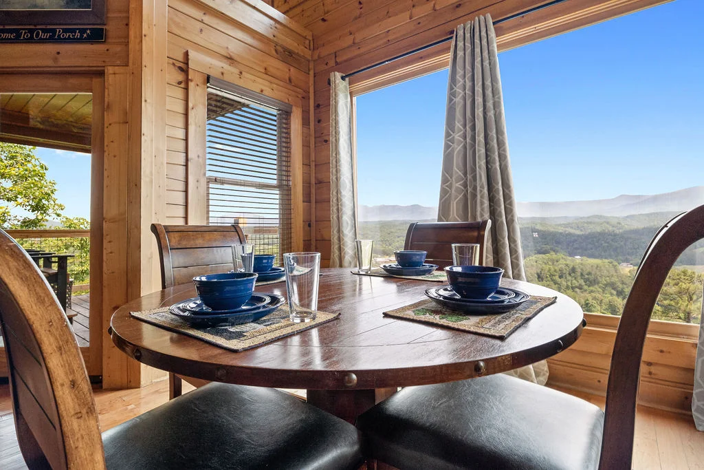 Rustic log cabin dining room with mountain views through windows at Bella Vista in Sevierville