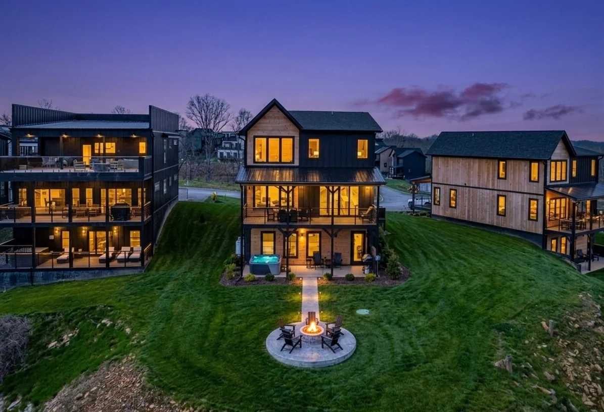 Aerial twilight view of luxury vacation rental homes in Pigeon Forge TN with illuminated interiors, fire pit, and mountain
