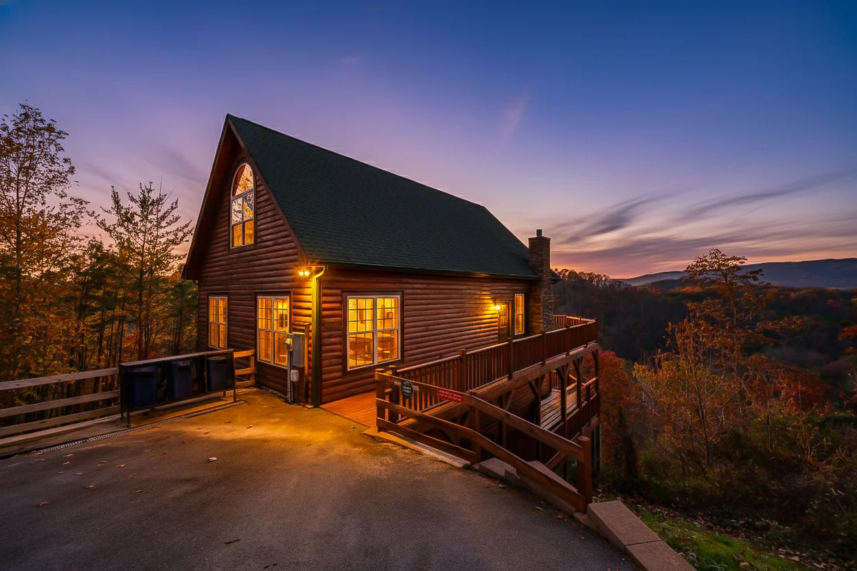 Illuminated log cabin at dusk with mountain valley view perfect for Smoky Mountains hikers