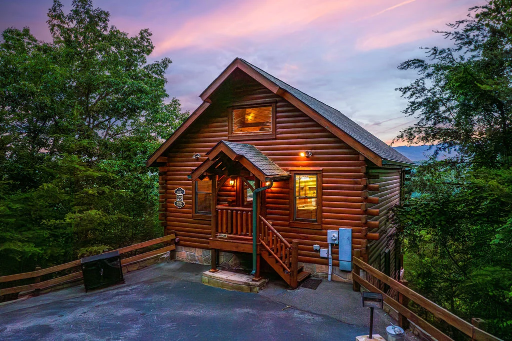 Luxury log cabin vacation rental illuminated at dusk with covered porch in Gatlinburg Tennessee