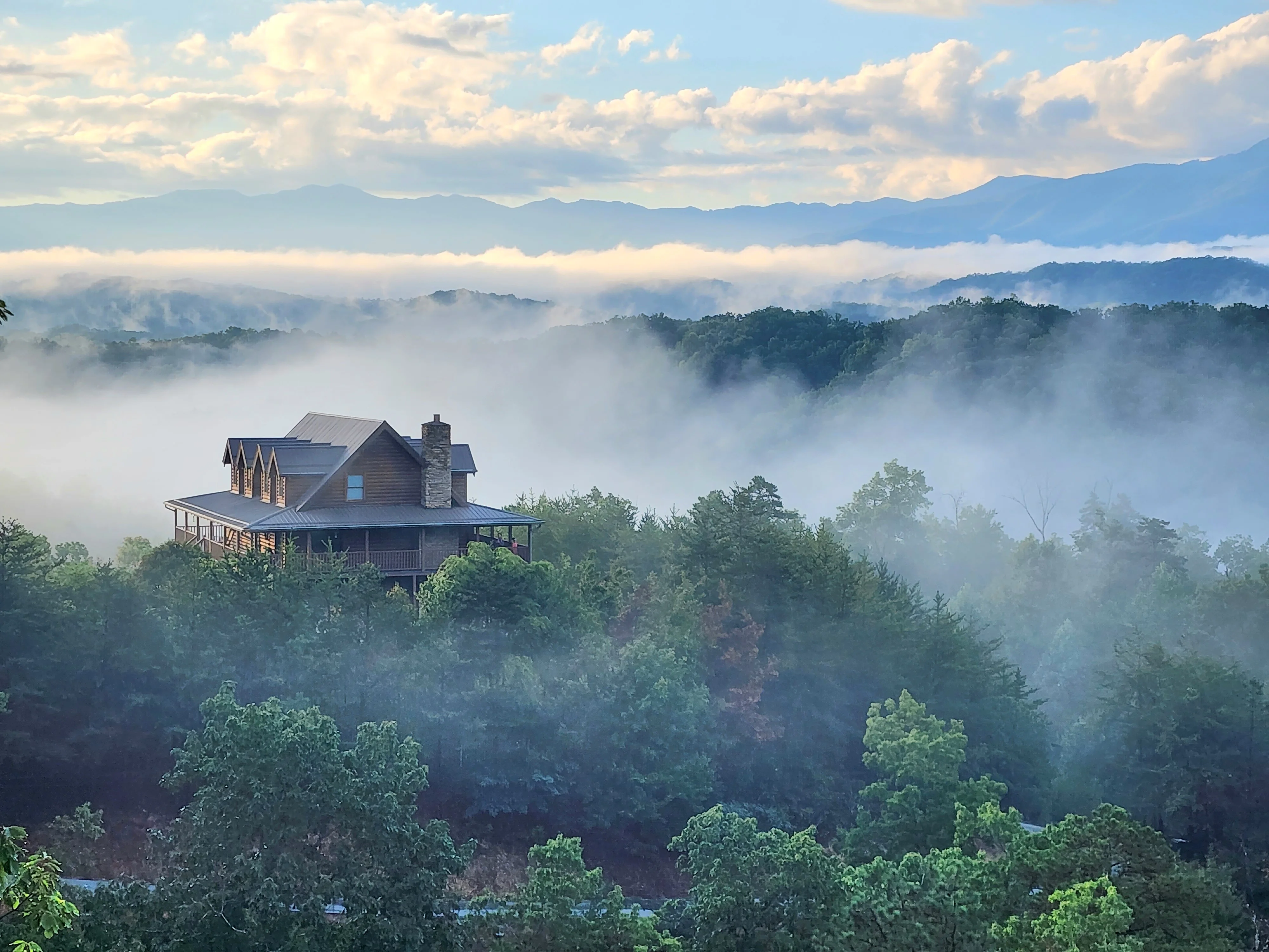 Mountain cabin with stone chimney overlooking misty Smoky Mountains valley on scenic Newfound Gap Road