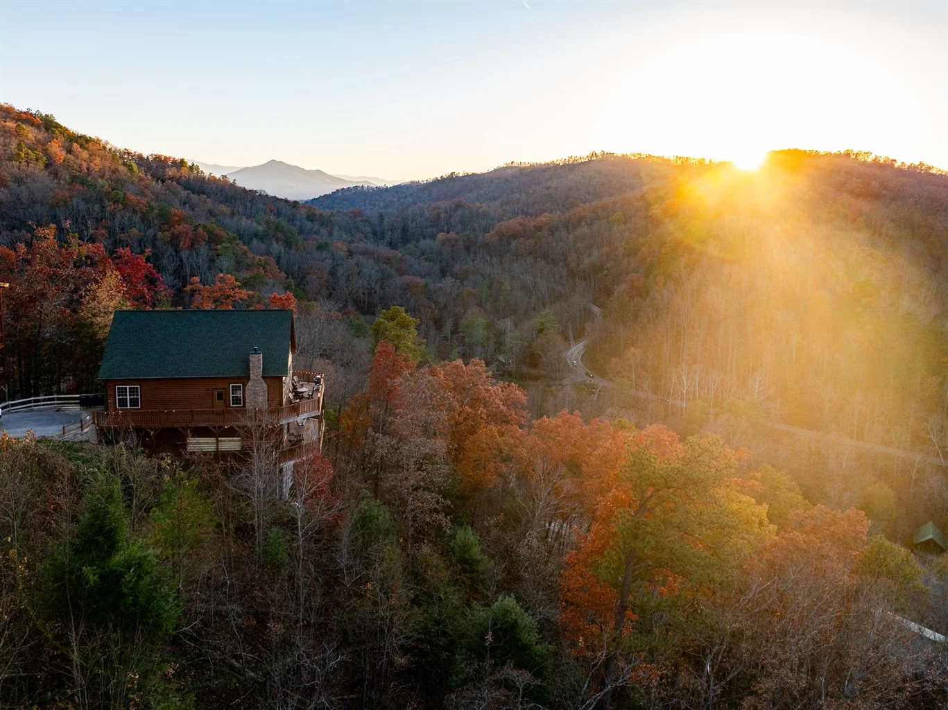 Covered deck with Adirondack chairs overlooking Smoky Mountains at sunset, showcasing premium cabin rental outdoor space