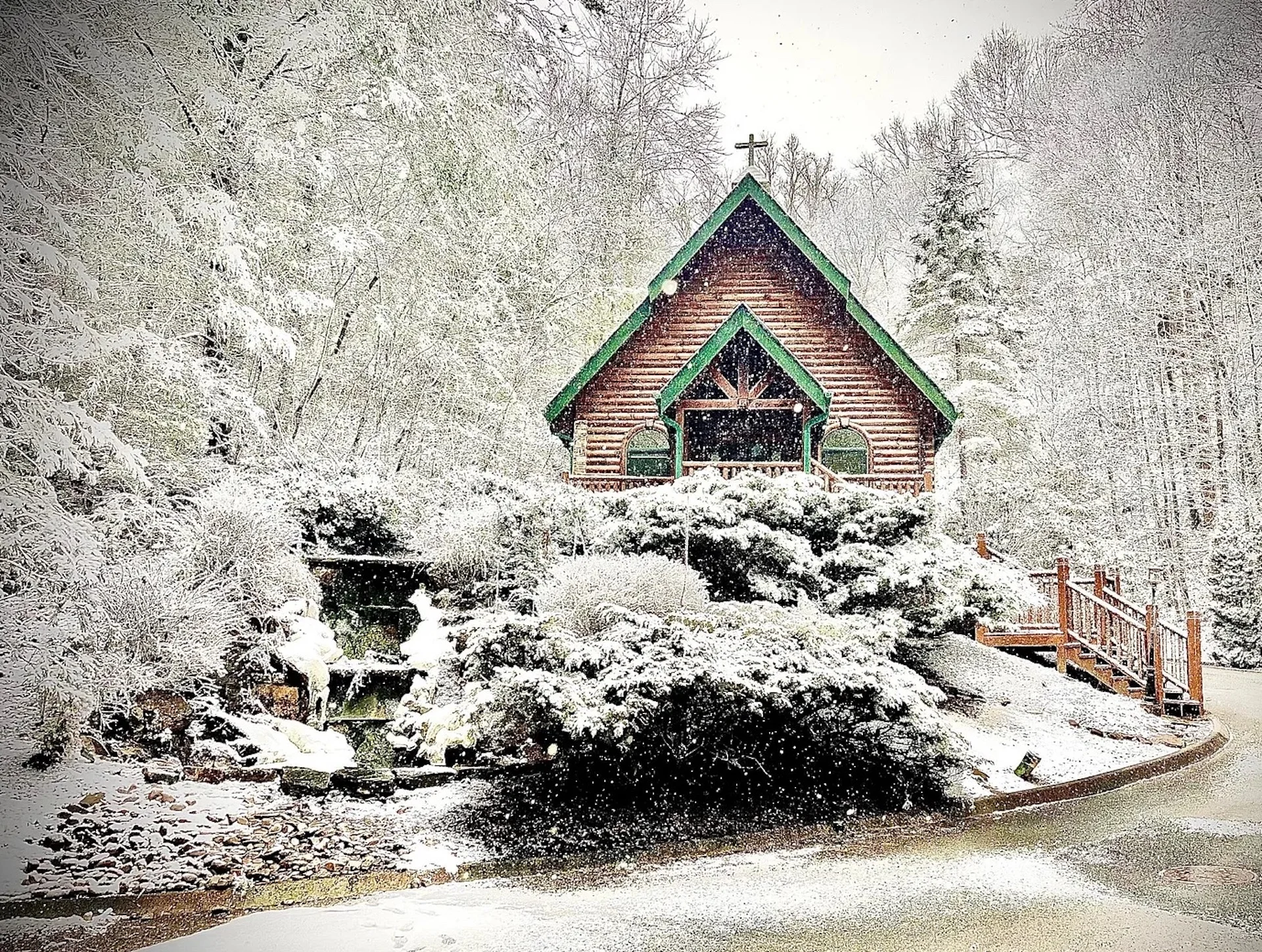 Log cabin chapel with green roof surrounded by snow-covered trees, offering winter solitude near Gatlinburg Tennessee