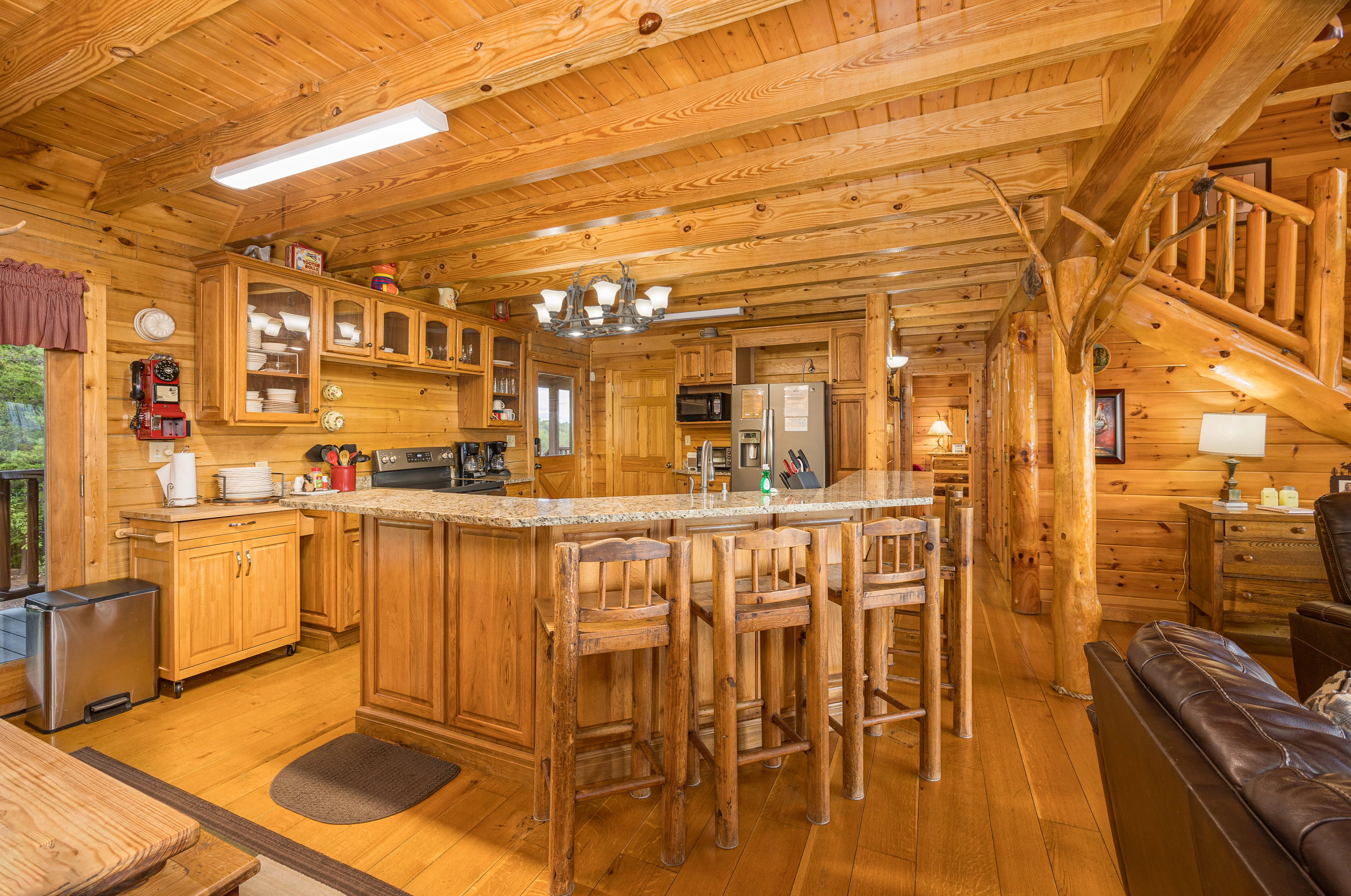 Log cabin kitchen with granite island and exposed beam ceilings in Sevierville Tennessee vacation rental