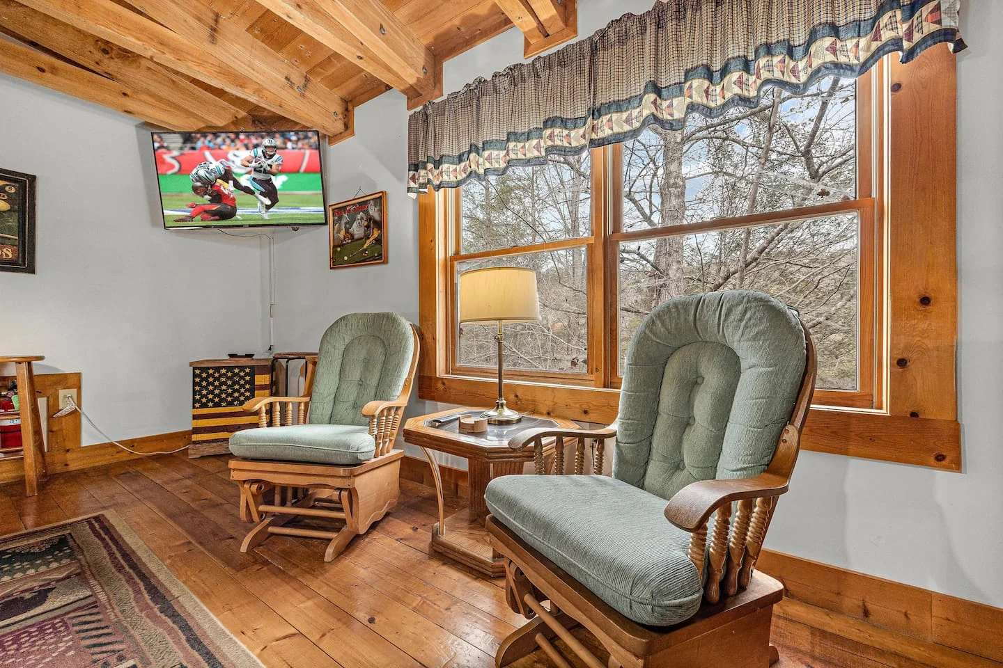Rustic Pigeon Forge cabin living room with wooden beams, rocking chairs, and large forest-view windows