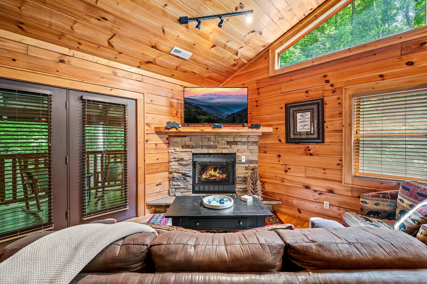 Rustic log cabin living room with stone fireplace and forest views, ideal base for Cades Cove loop drive