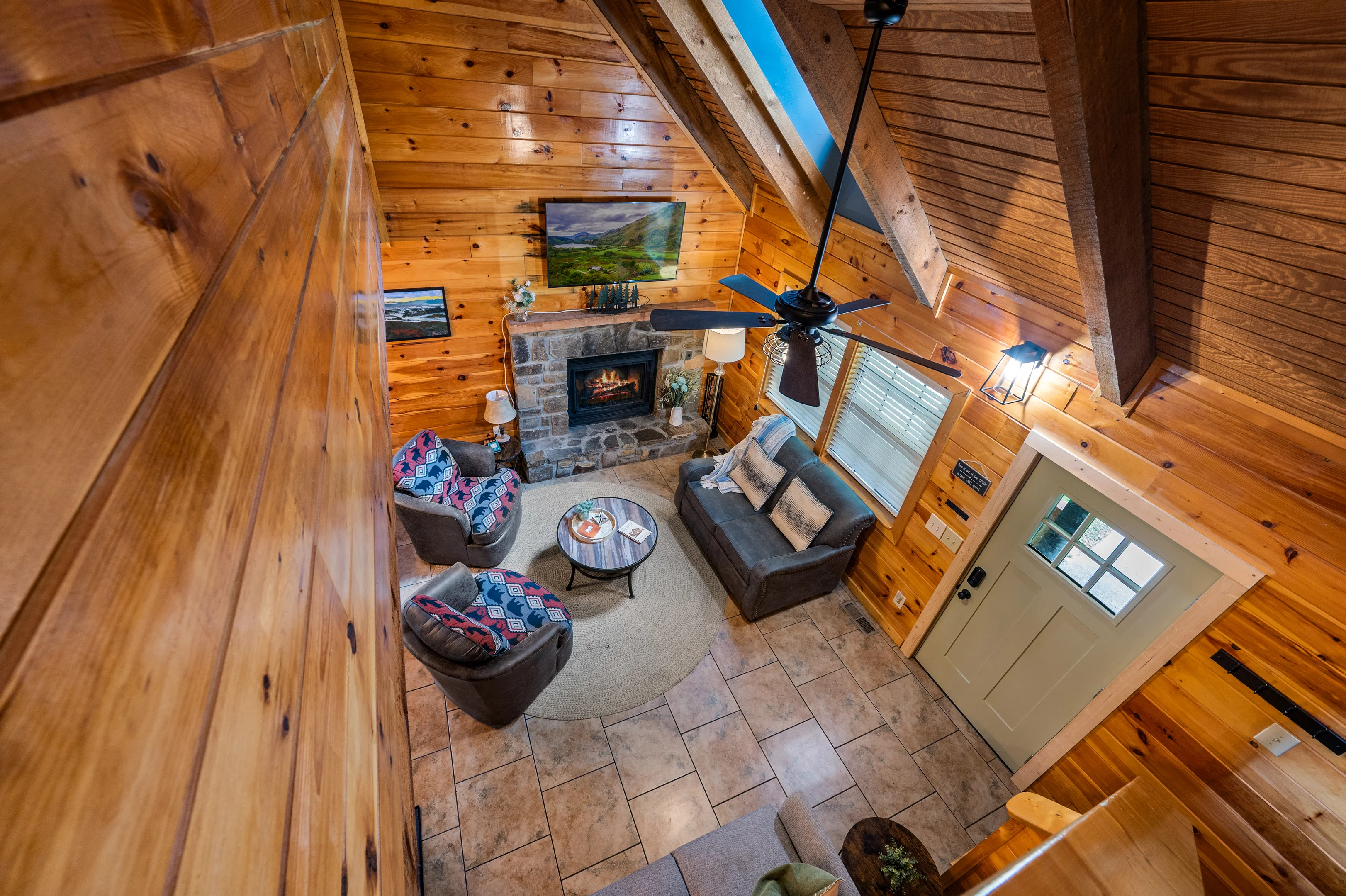 Rustic log cabin living room at Wandering Oak vacation rental in Pigeon Forge Tennessee featuring stone fireplace, vaulted